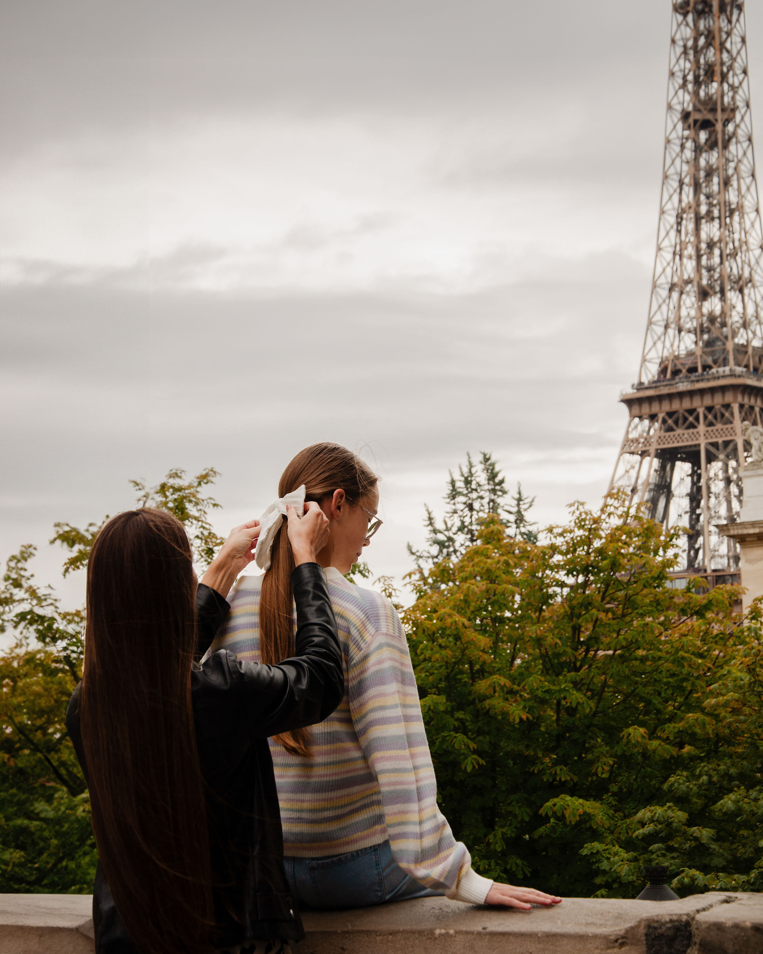 Мама поправляет бант дочери во время семейной фотосессии в Париже