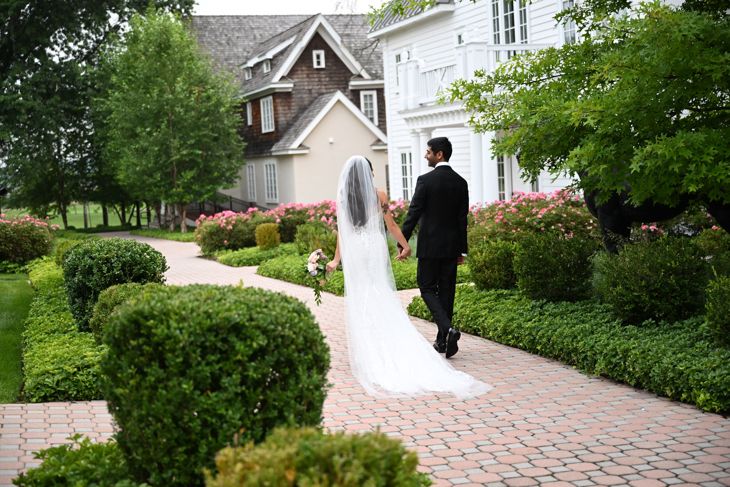 a bride and groom walking down a brick path
