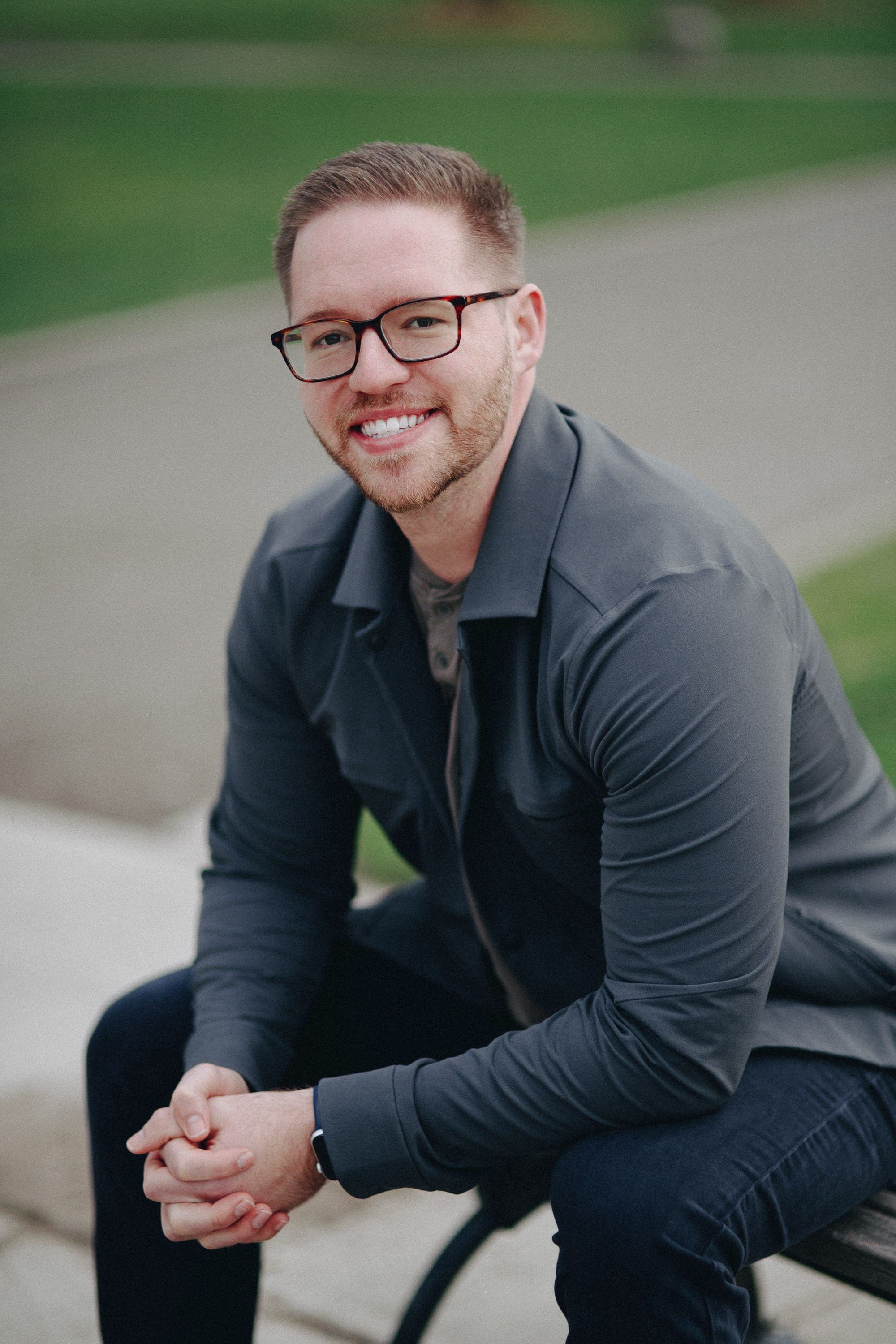 Smiling man sitting on a bench with hands clasped