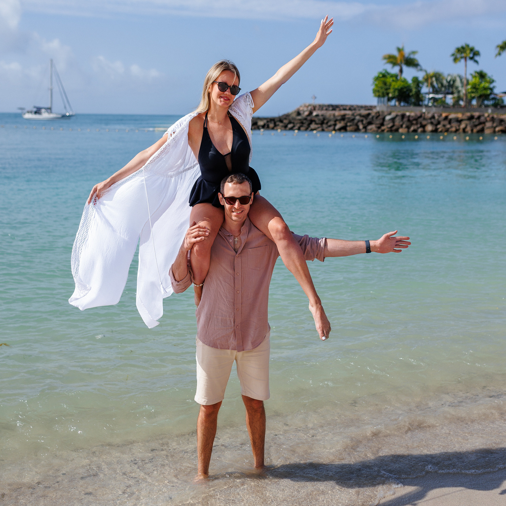 Love Story Photographer: Anfi Beach, Canary Island A couple sitting on the beach with a boat in the background.