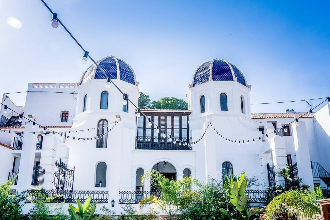 La Campaneta wedding venue with a white façade, twin blue-tiled domes and festoon lights above the garden.