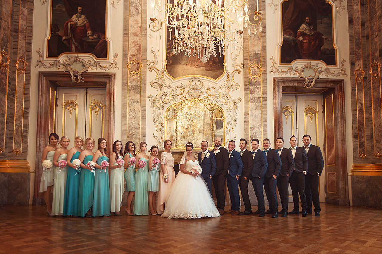 Gruppenportrait im Schloss Bruchsal mit strahlendem Brautpaar und Hochzeitsgästen