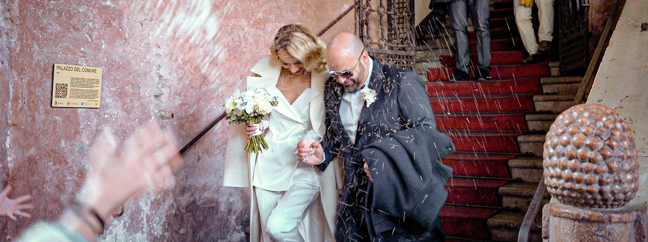 Newlyweds leaving the ceremony under a shower of petals – official wedding in Italy
