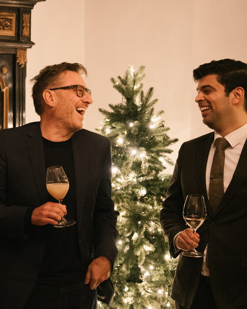 Guests in suits chatting and holding champagne glasses at an elegant company Christmas reception