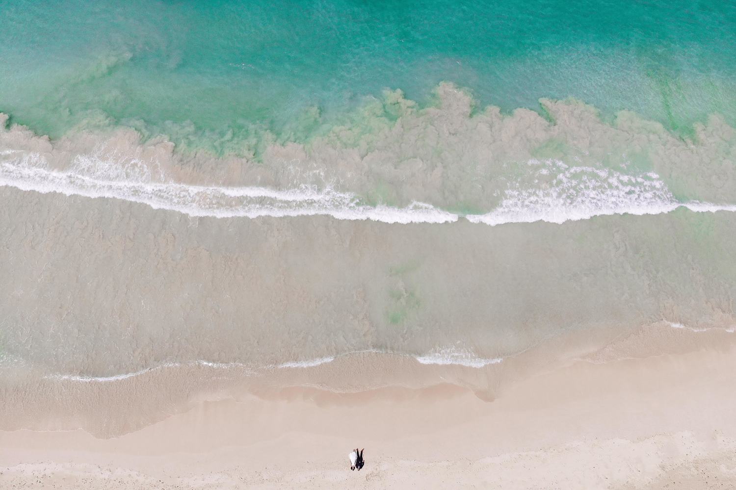 Невеста и жених лежат на пляже возле океана.