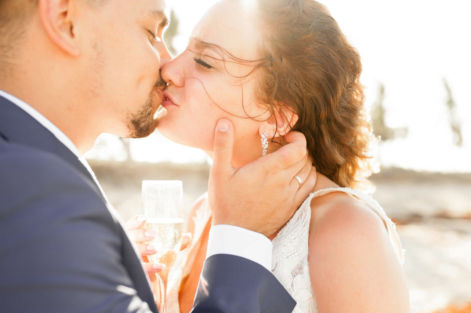 Newlyweds kissing on the beach in the sunset.