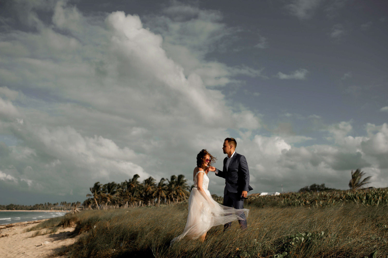The groom holds the bride's hand on the beach in Macaо.
