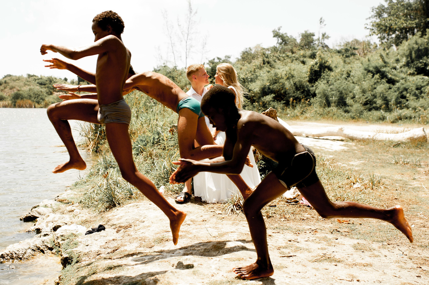 The bride kisses the groom in time for the local children to run by.