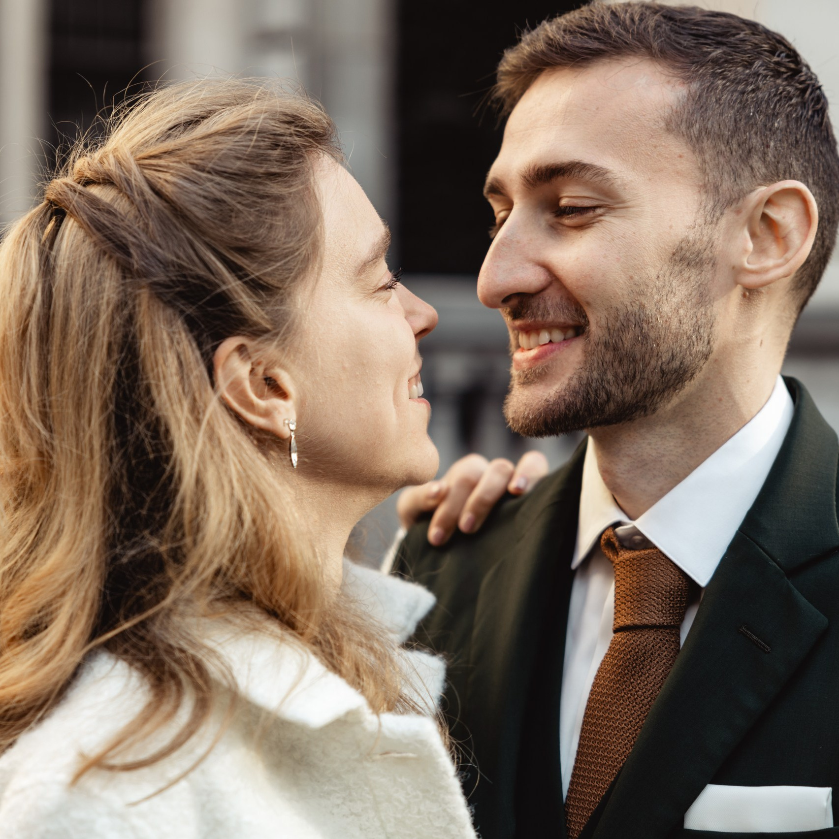Het bruidspaar kijkt elkaar glimlachend aan tijdens een intiem moment op straat.