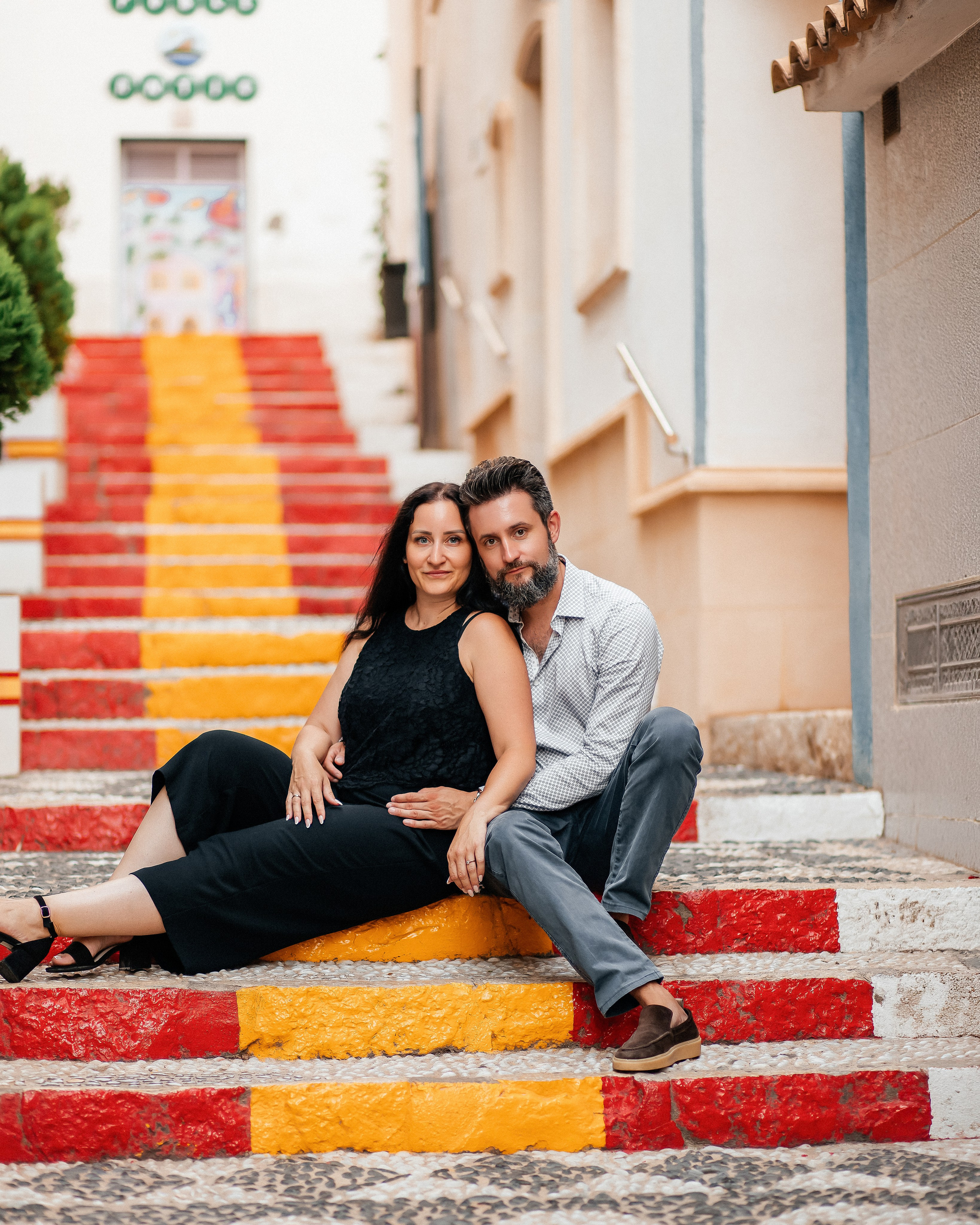 Couple sitting together on colorful steps during a romantic photoshoot in Alicante, Costa Blanca, Spain