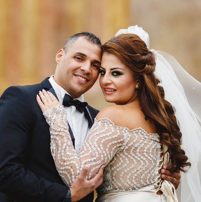 Red-haired bride holding her flowing veil aloft smiles seductively to her bouquet holding groom as he leans back against a railing in appreciation at the Vrtba Garden in Prague. 