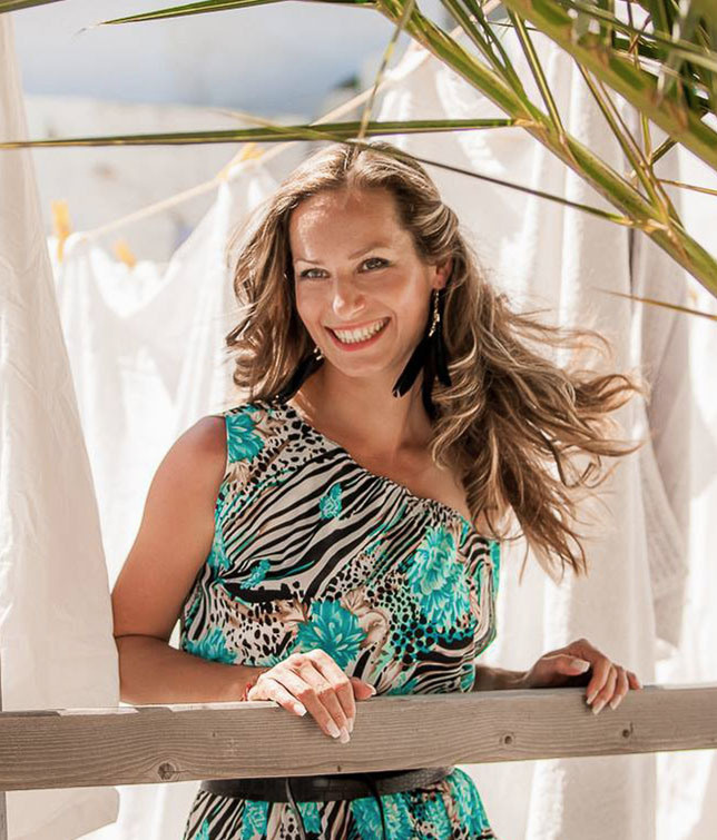 Екатерина Романова улыбается, волосы развеваются. Организатор свадеб в Греции на Крите и Санторини, фотограф.