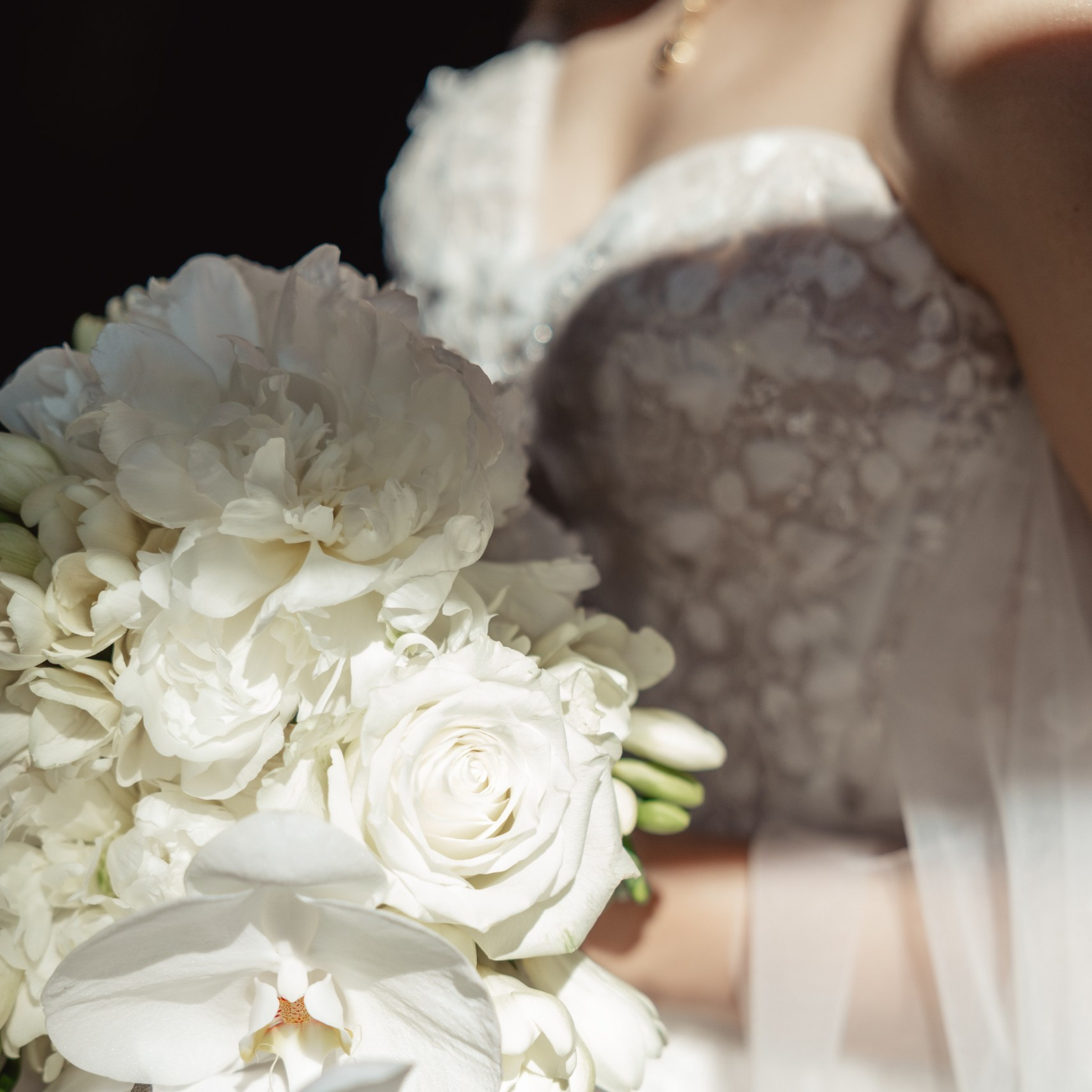 Detail van het bruidsboeket en de trouwjurk