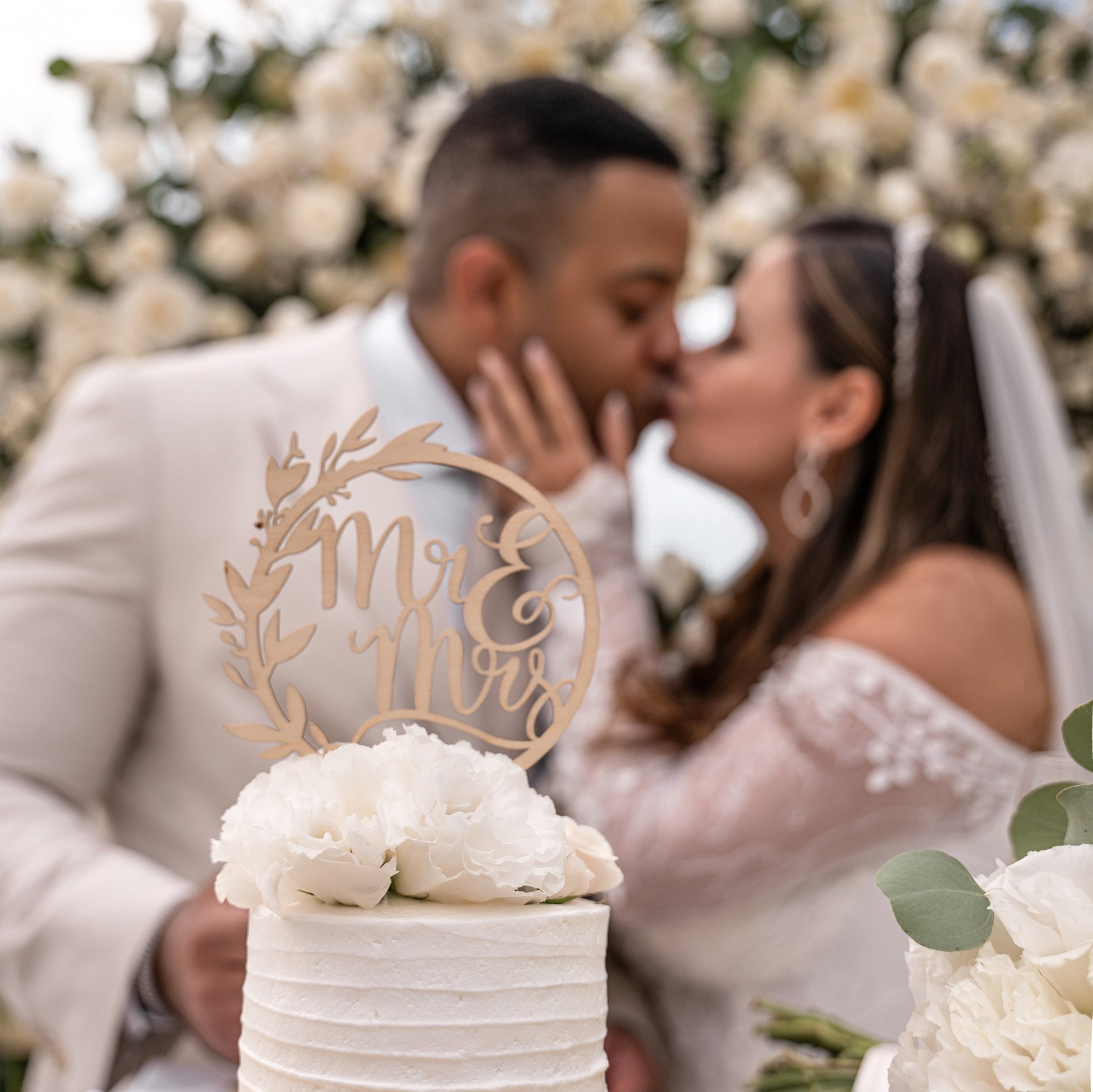 The bride and groom kiss in front of the cake in Cancun.