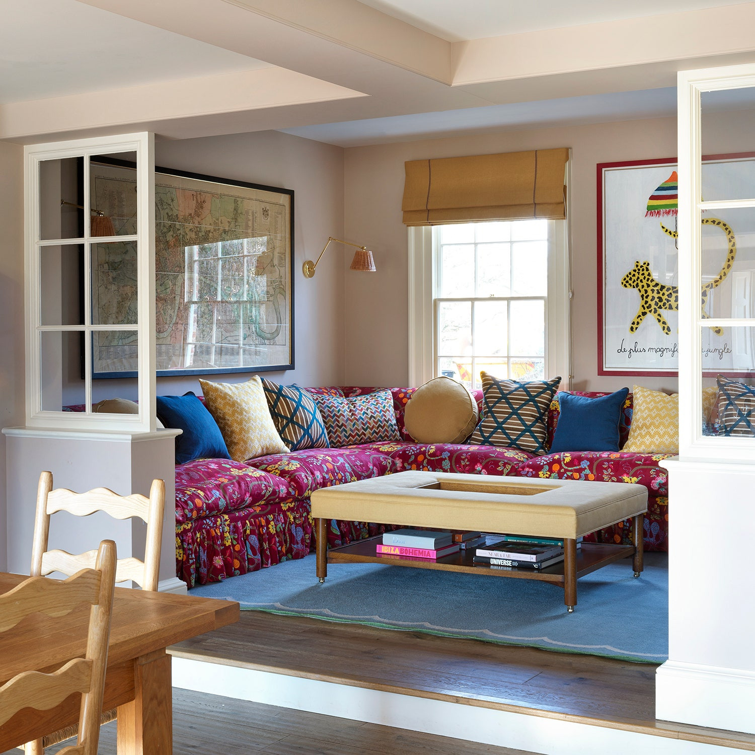 Colorful floral sectional sofa with pillows and beige ottoman