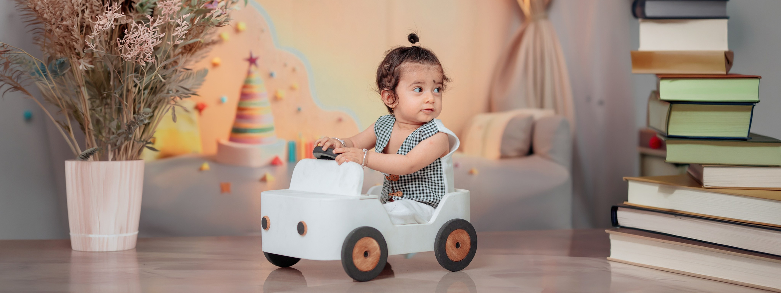 A cute baby boy sitting in a white toy car during her first birthday photoshoot in Butwal