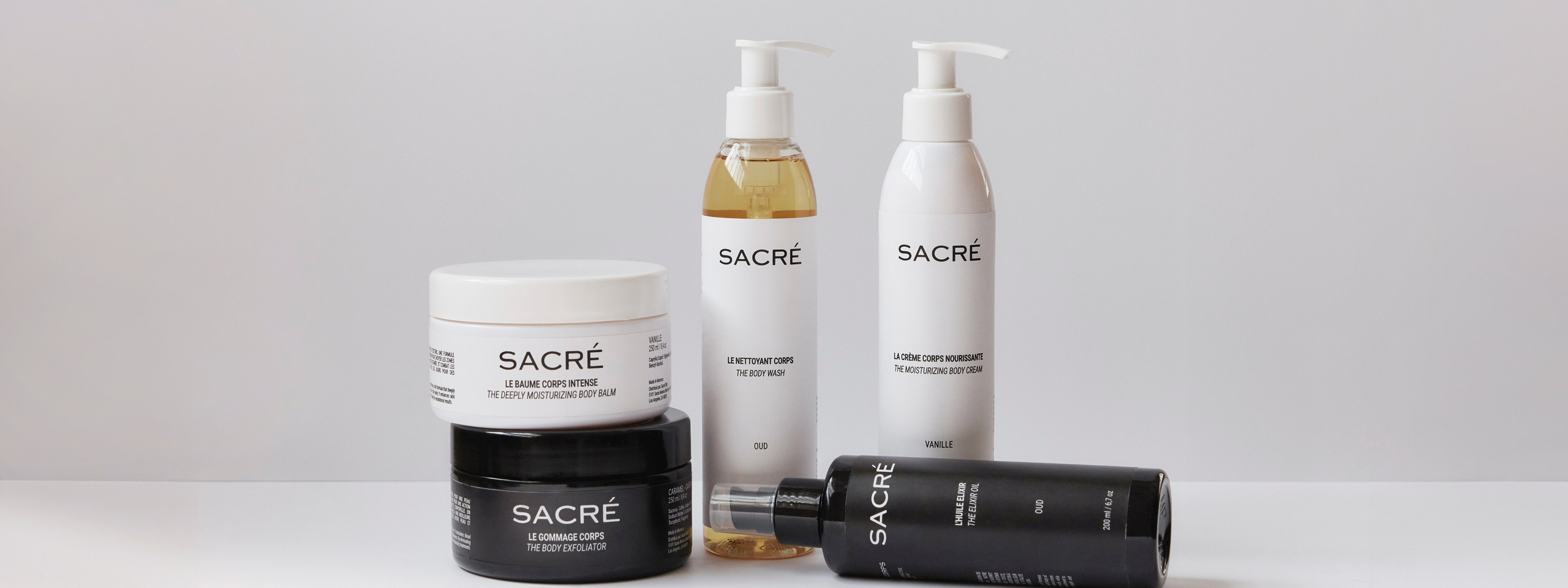 Product lineup of Sacré skincare, including body balm, body wash, and elixir oil, showcasing luxury and natural beauty.