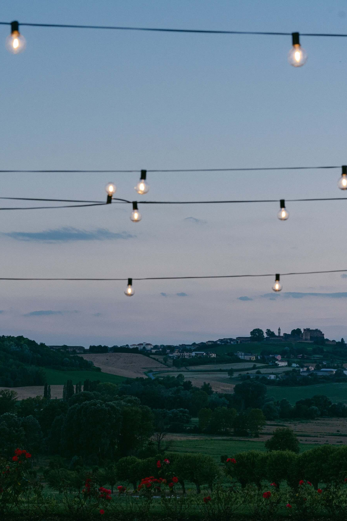 String lights above the Langhe hills at dusk at a Piedmont wedding venue