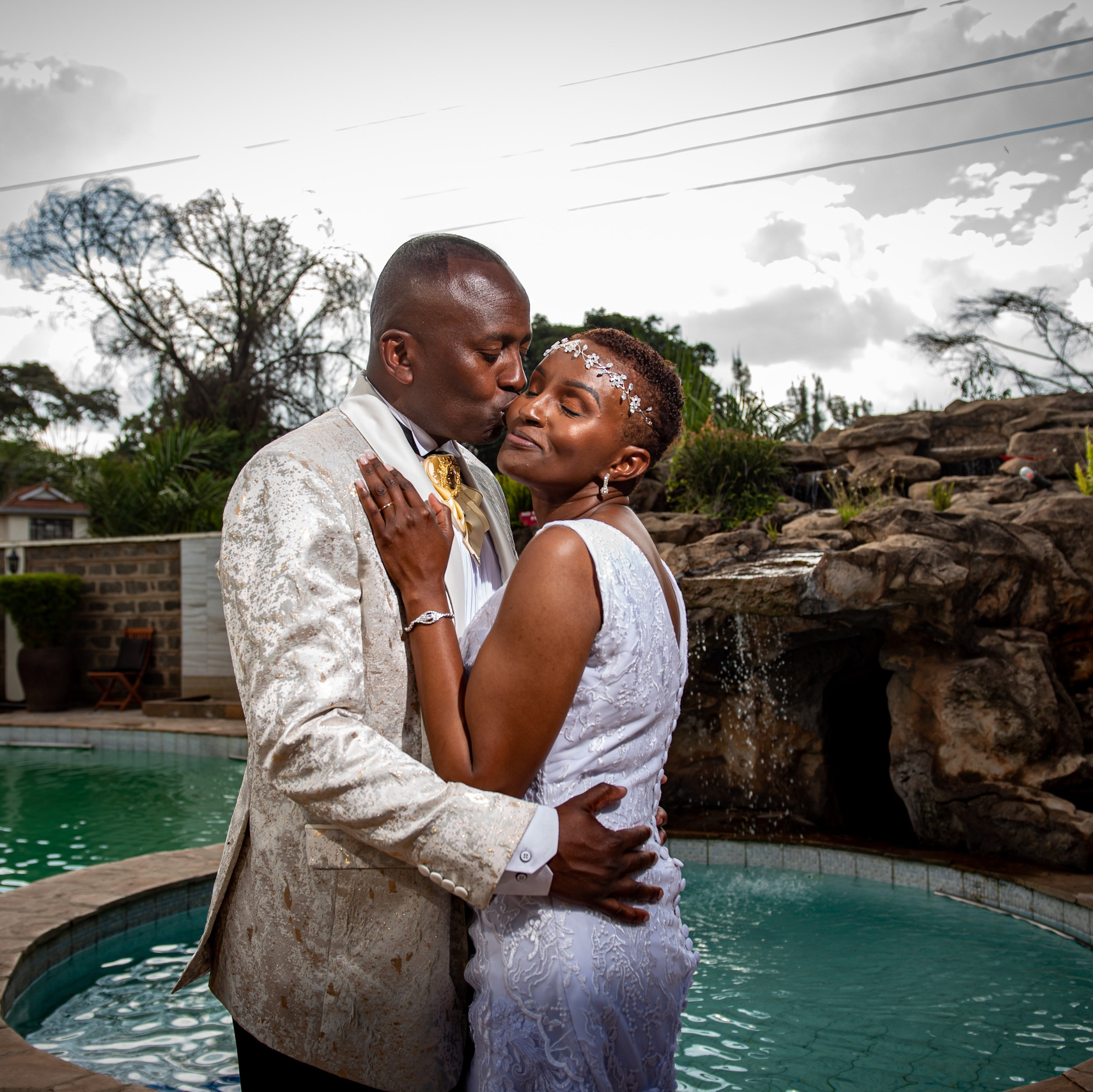 A portrait of a groom embracing his bride next to a pool, at a wedding held Karen in Nairobi.