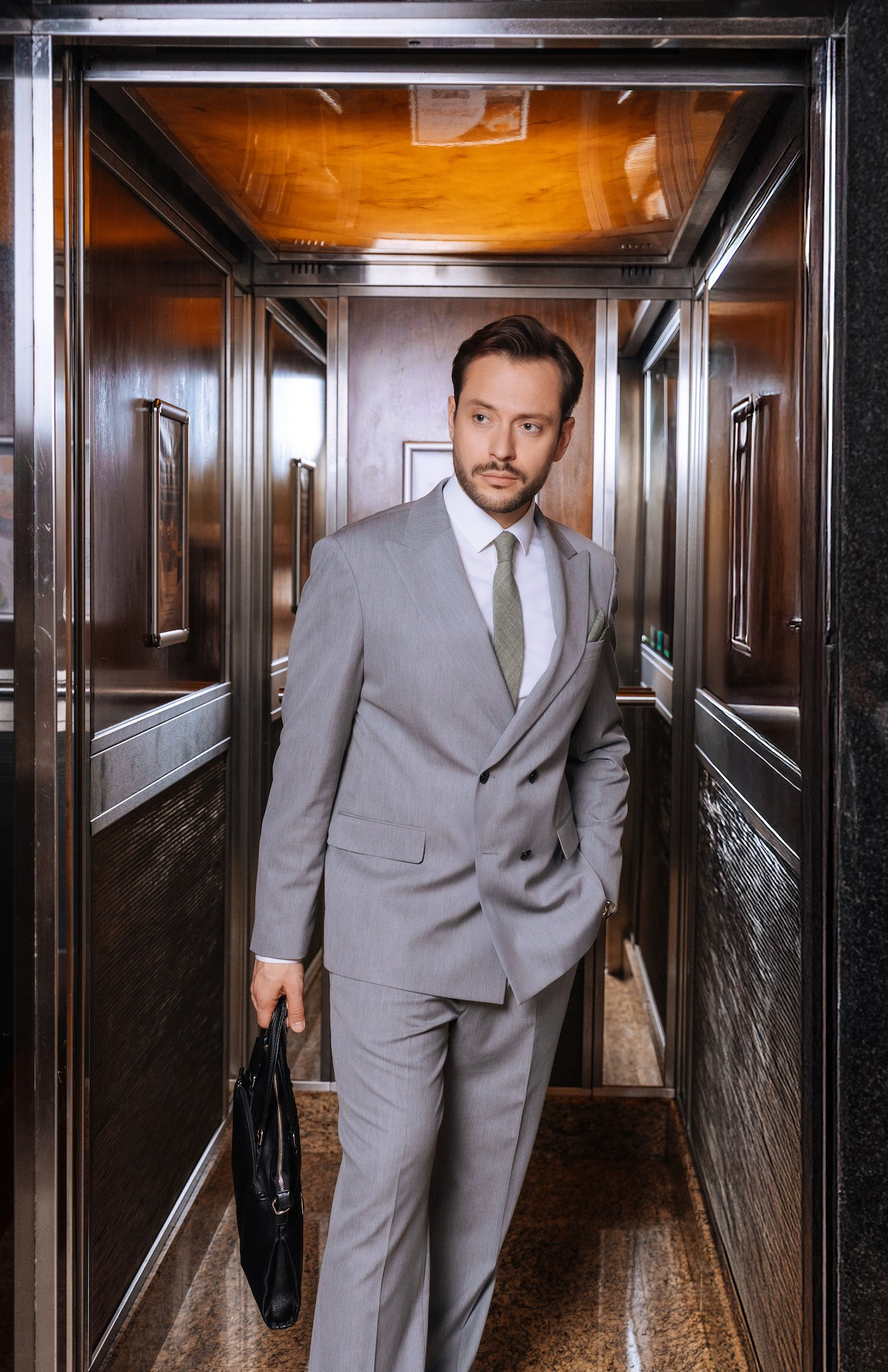 Деловой человек выходит из лифта с кейсом в отеле