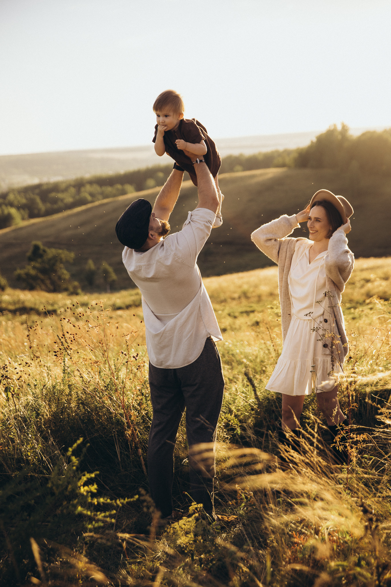 famille avec un enfant dans la champ sous le coucher du soleil