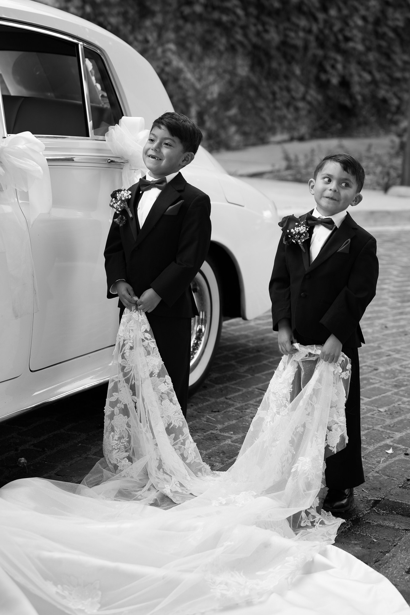 Kids holding the veil and looking at the bride with smiles