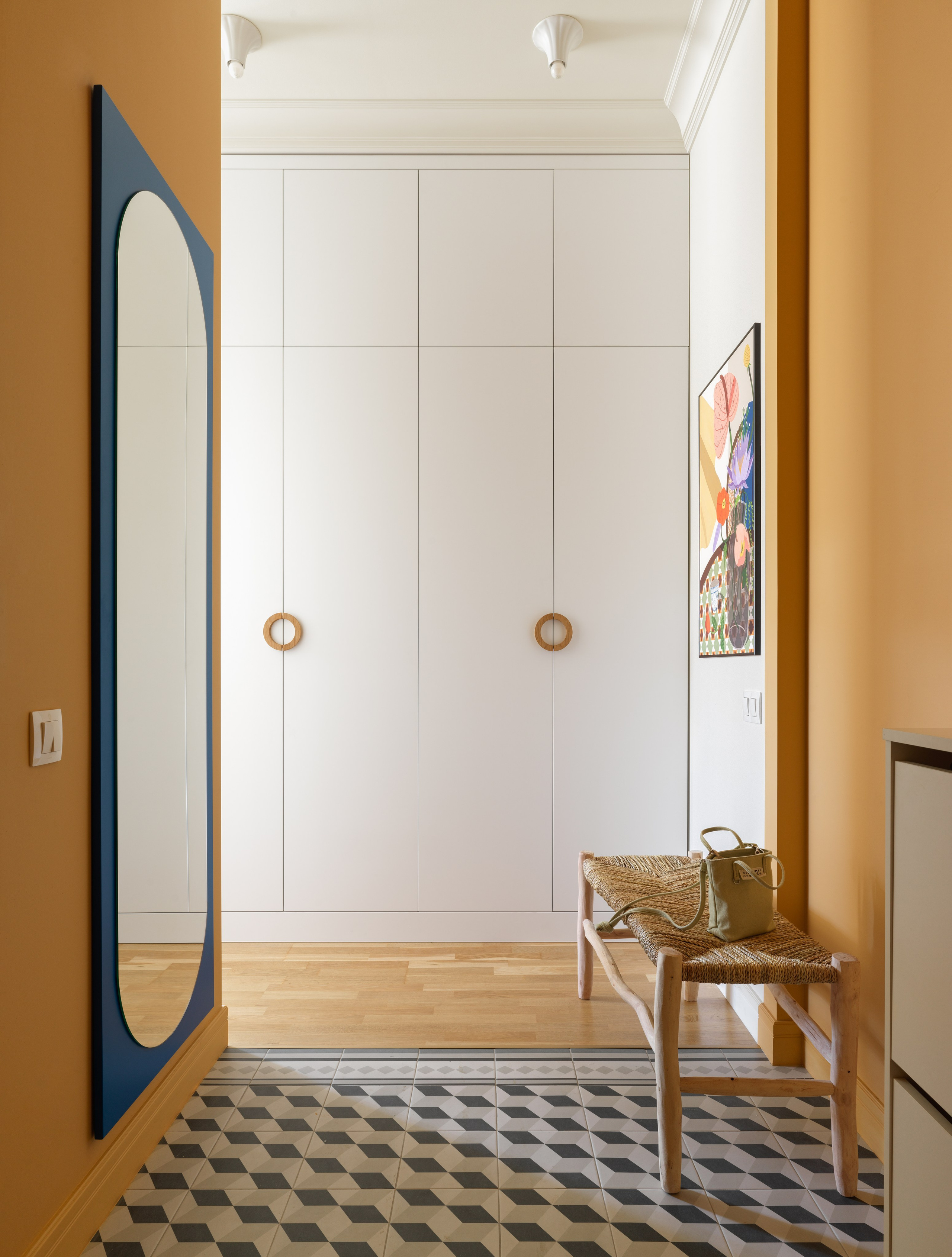 Коридор с овальным зеркалом в раме из МДФ и деревянной скамейкой с плетением.