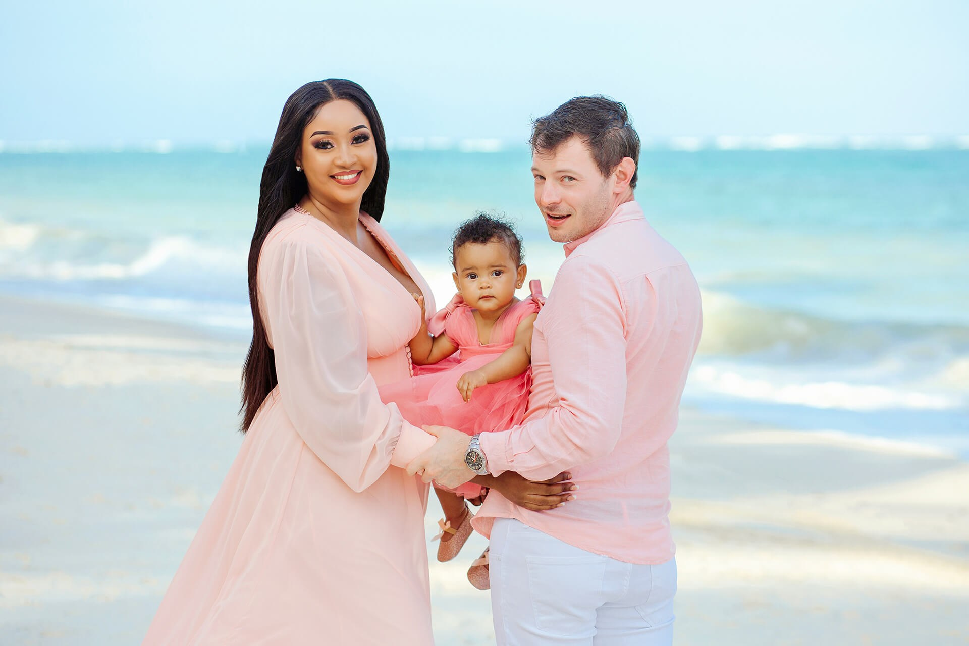 Couple embracing by the sea in soft morning light – family with baby photo shoot, Leopard Beach, Diani Kenya
