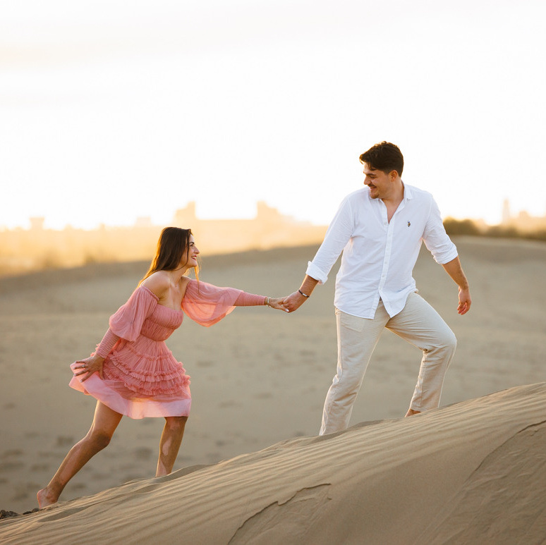 Love Photo Shoot A couple holding hands on a sand dune at sunset