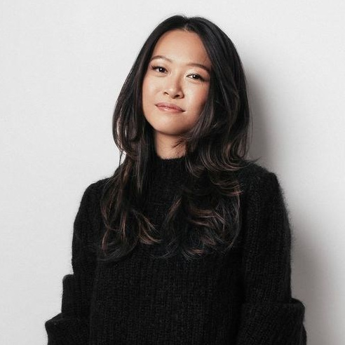 Confident woman in a cozy black sweater, looking directly at the camera against a light backdrop