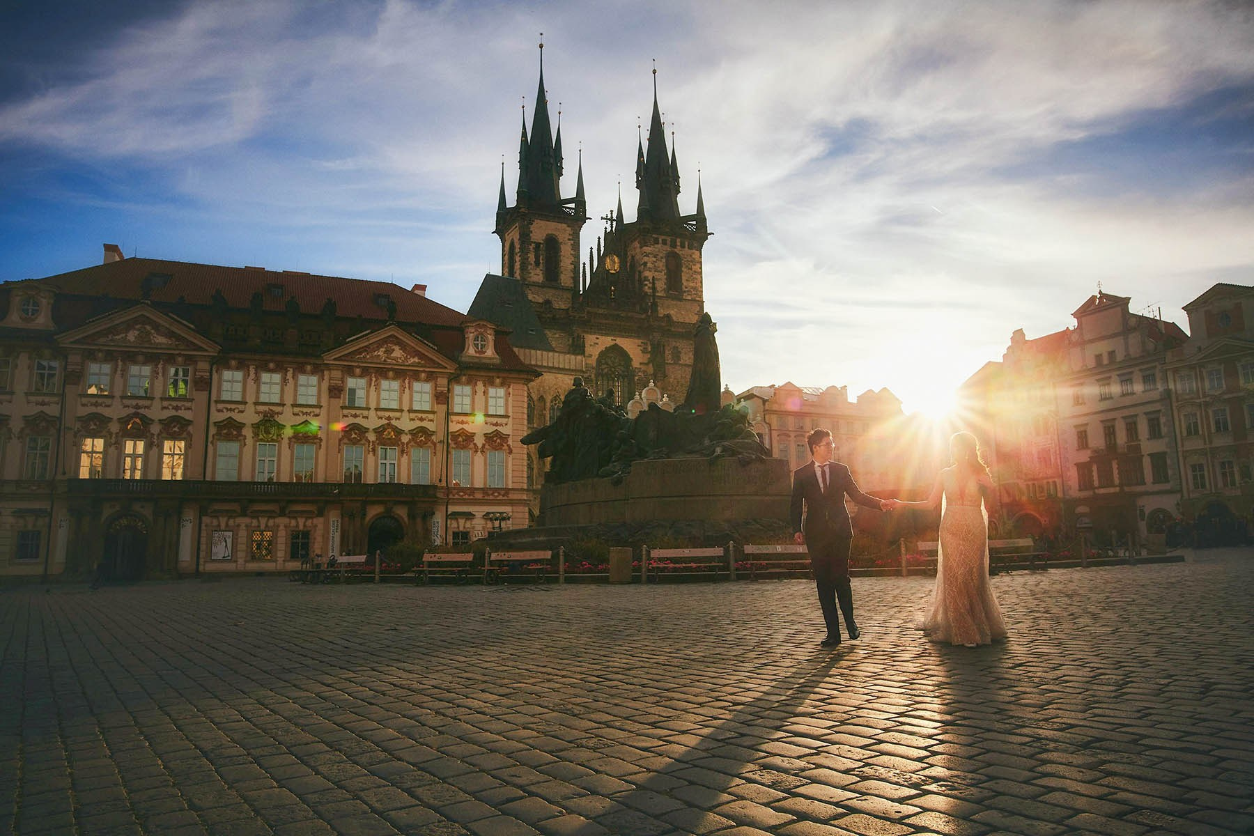 Couple running across empty Old Town Square at sunrise in Prague.
