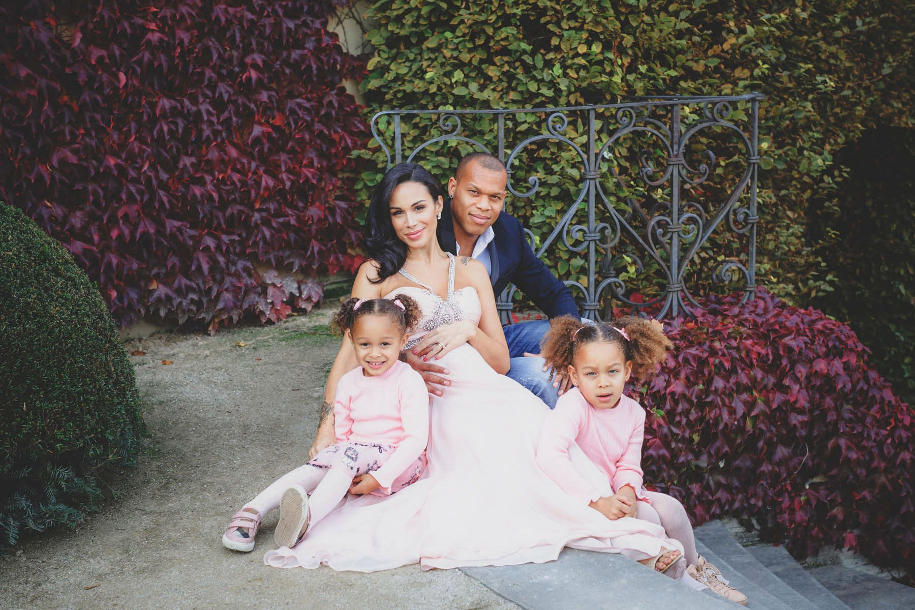 Family of four seated on stone steps in front of ivy at Vrtba Garden