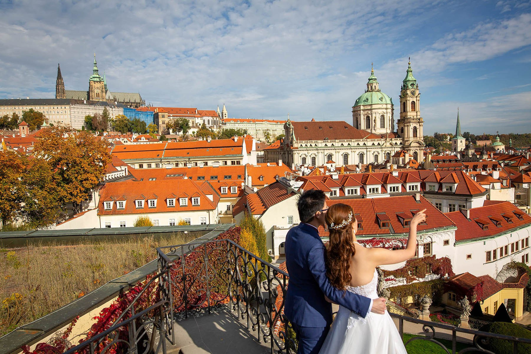 Couple pointing across Mala Strana view with St. Nicholas, Prague.