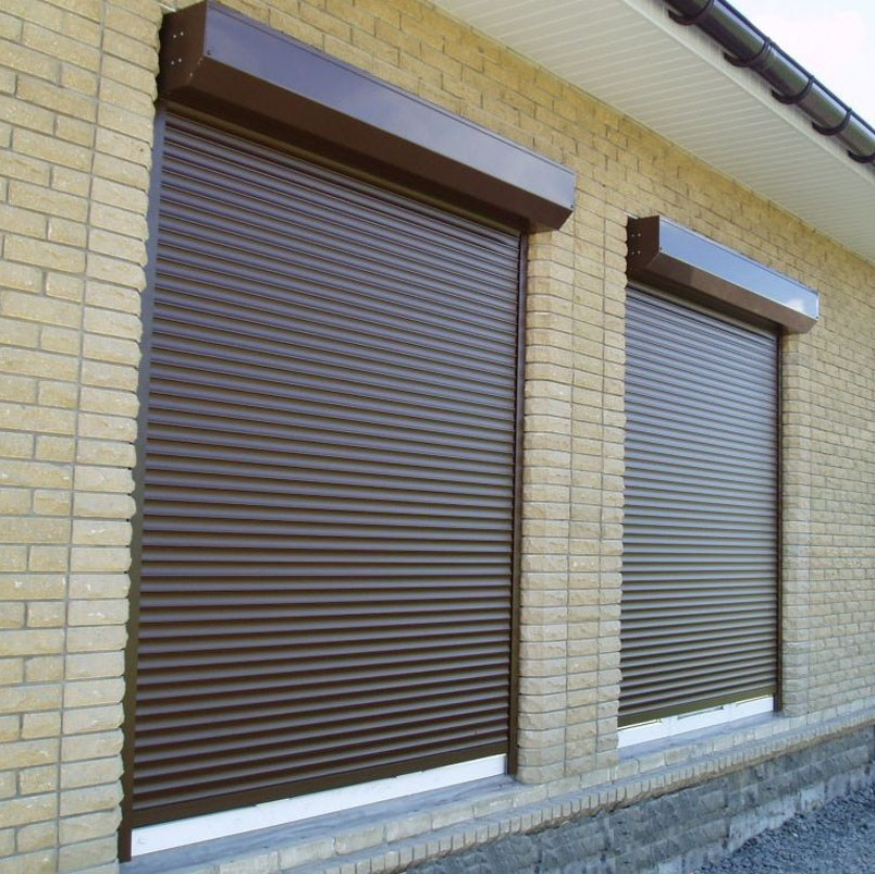Роллеты коричневого цвета установленные на облицованной светлым кирпичом стене способом: Накладной монтаж наружный.
