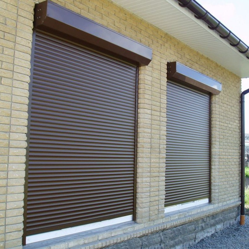 Проемы в кирпичной стене закрыты роллетами коричневого цвета.