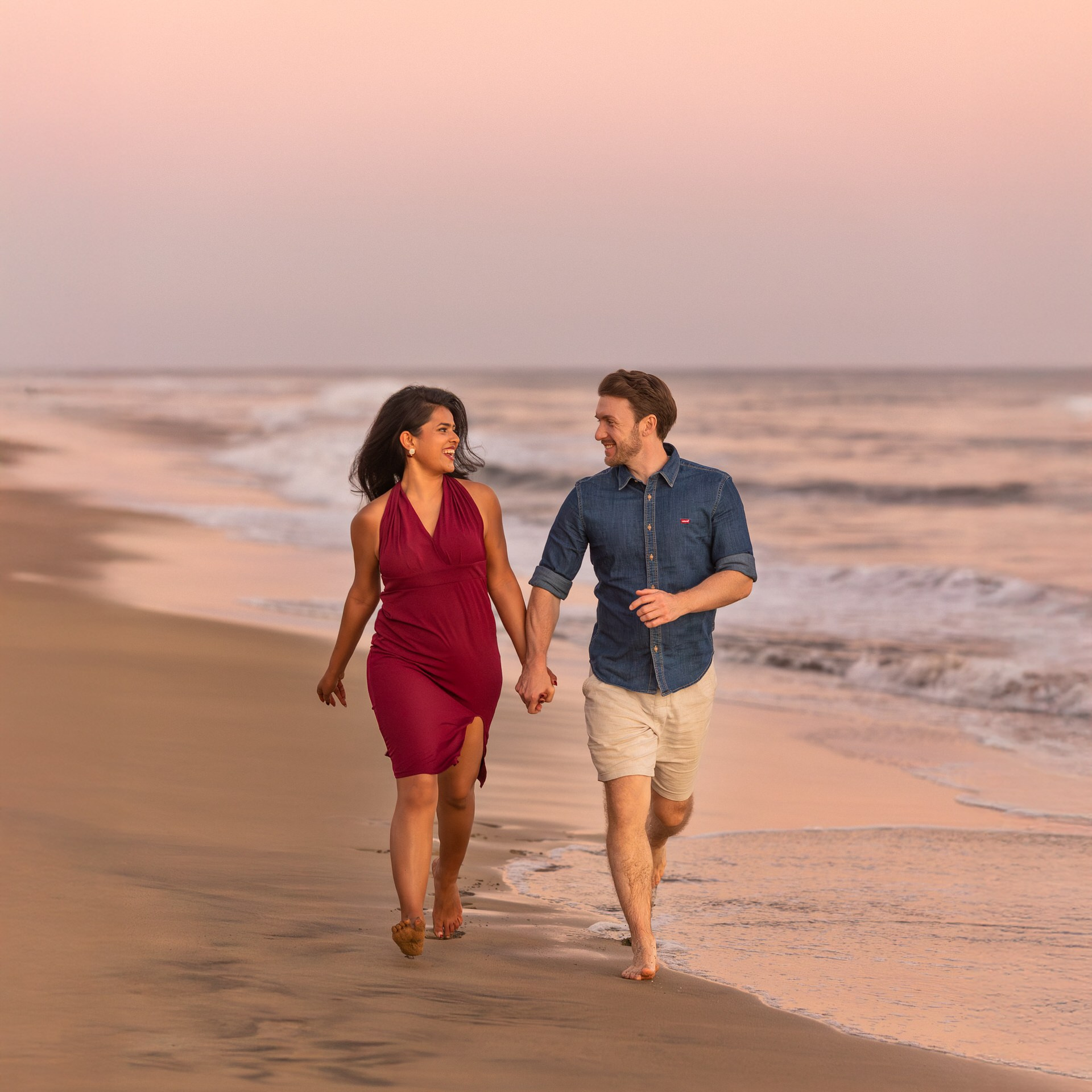 A couple walks hand in hand along the shoreline at sunset on Maspalomas for an engagement photoshoot.