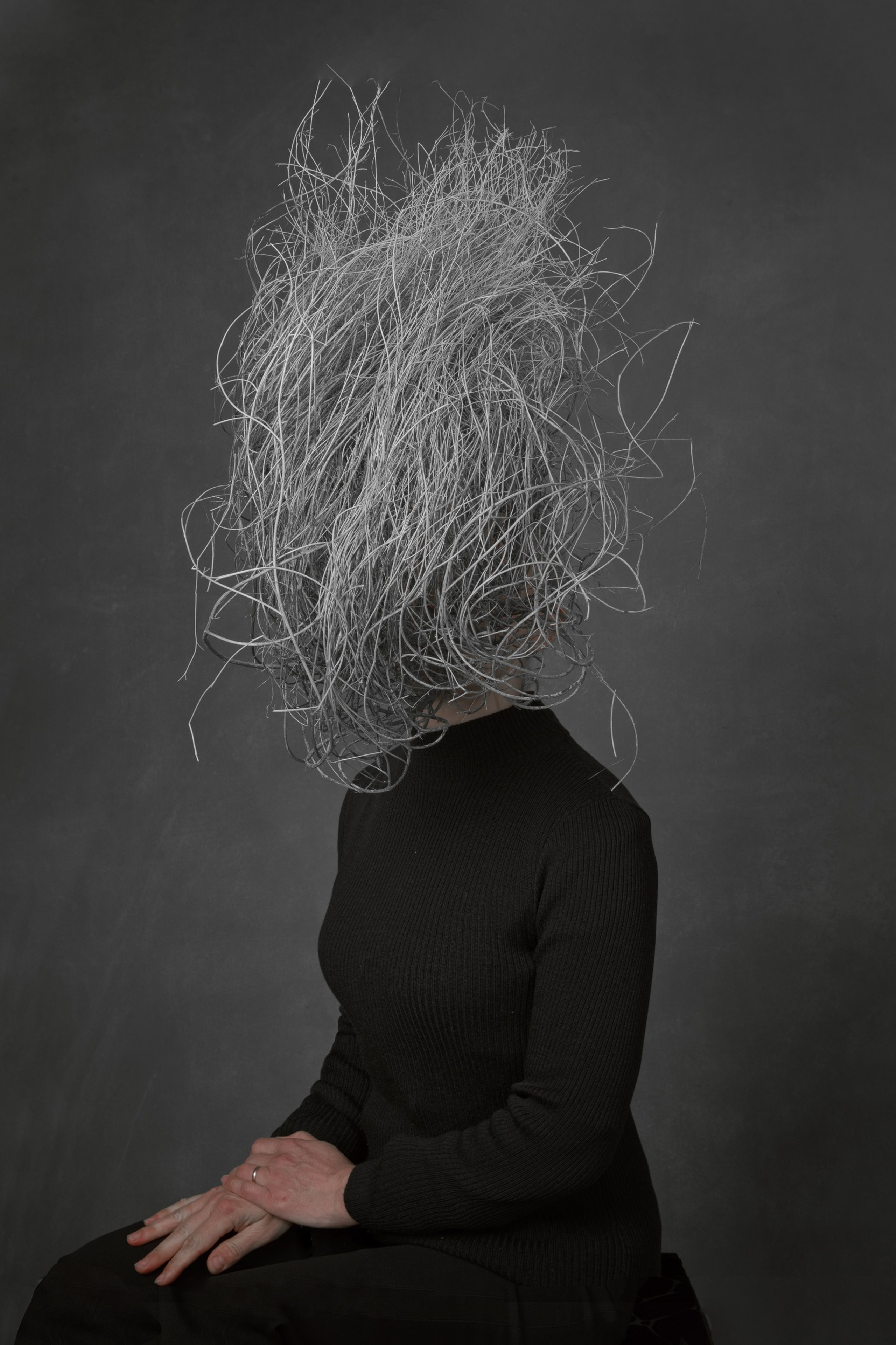 Black and white image of a person in a black, Instead of a head, there is a cluster of branches