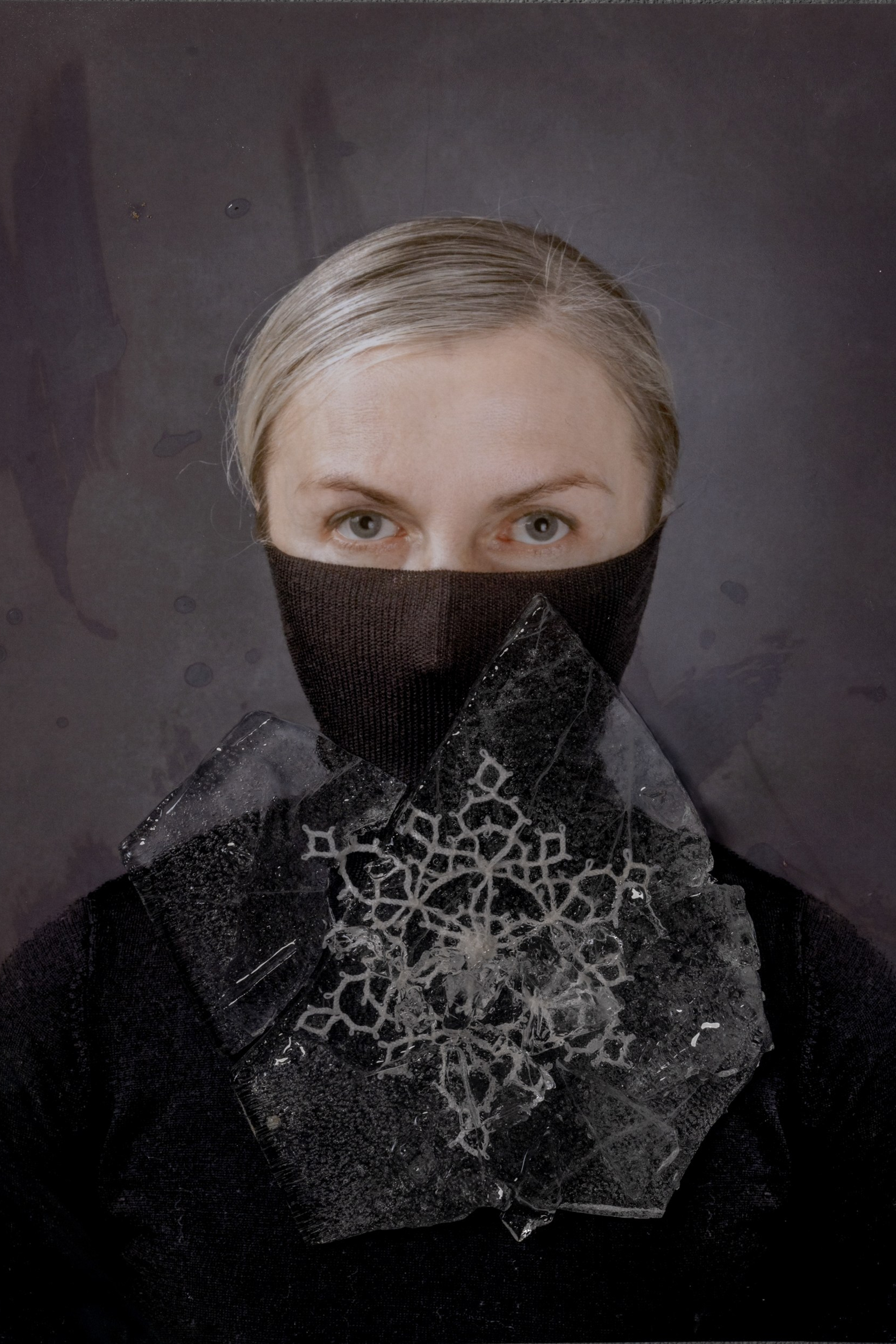 Portrait of a woman in black with mouth covered and lace frozen in cracked ice on her neck, symbolizing emotional silence, memory repression, and the fragile power of expression – fine art photography by Maria Tulchinskaya.