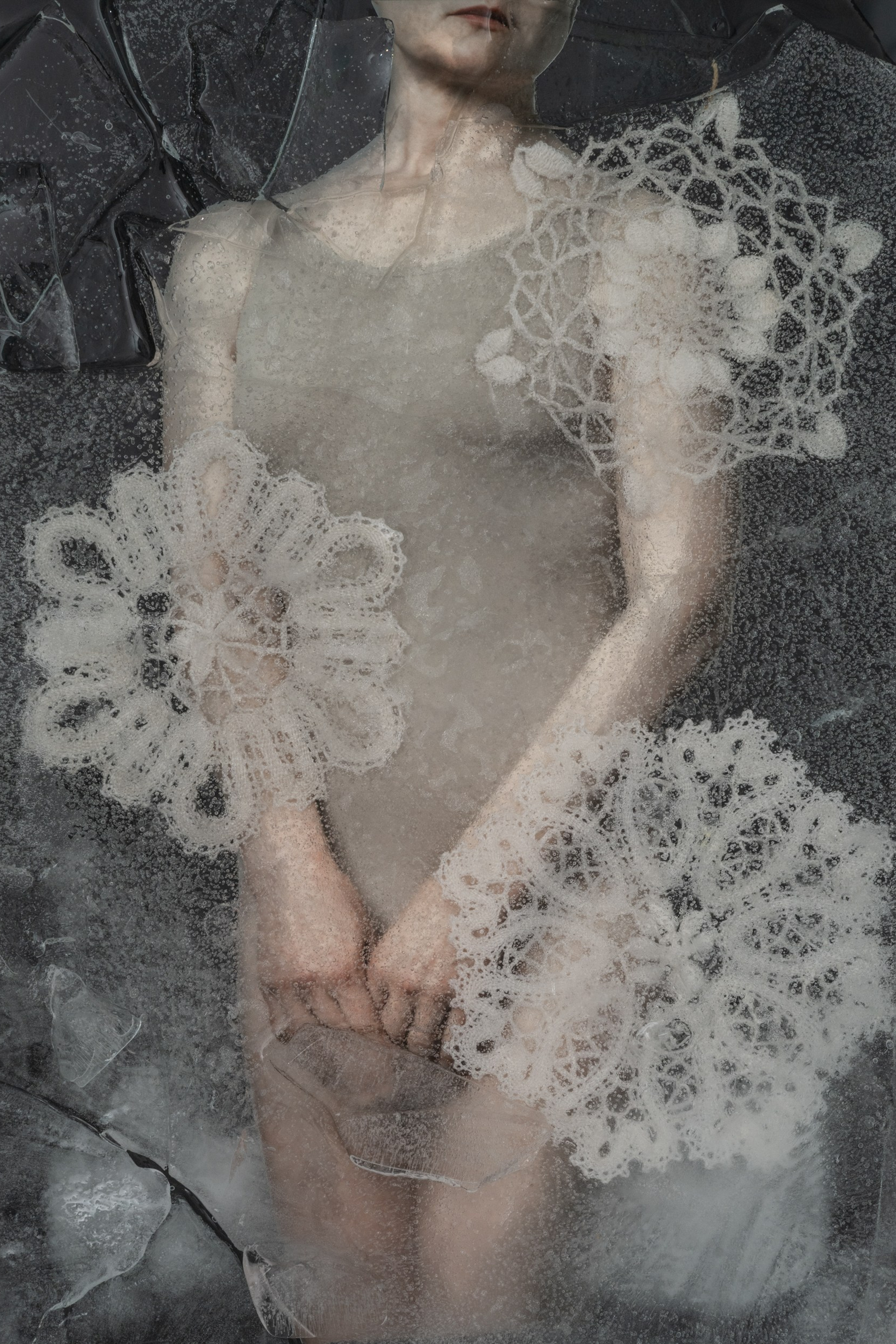 Artistic portrait of a woman behind cracked ice, with frozen lace patterns symbolizing memory, silence, and emotional preservation – fine art conceptual photography by Maria Tulchinskaya.