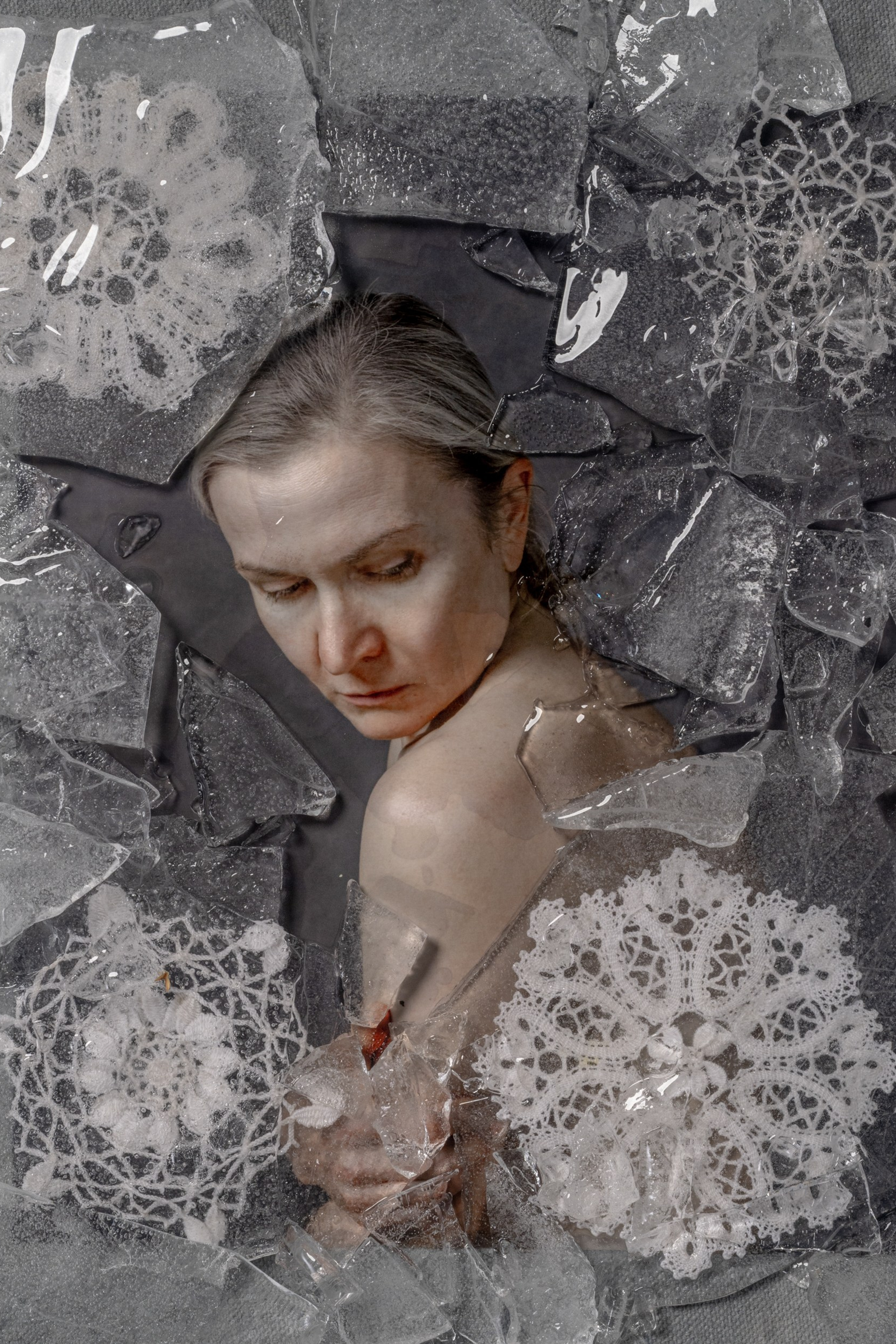 Fine art portrait of a woman enclosed in cracked ice and frozen lace, symbolizing suppressed memory, inherited silence, and the beginning of emotional release – by Maria Tulchinskaya.