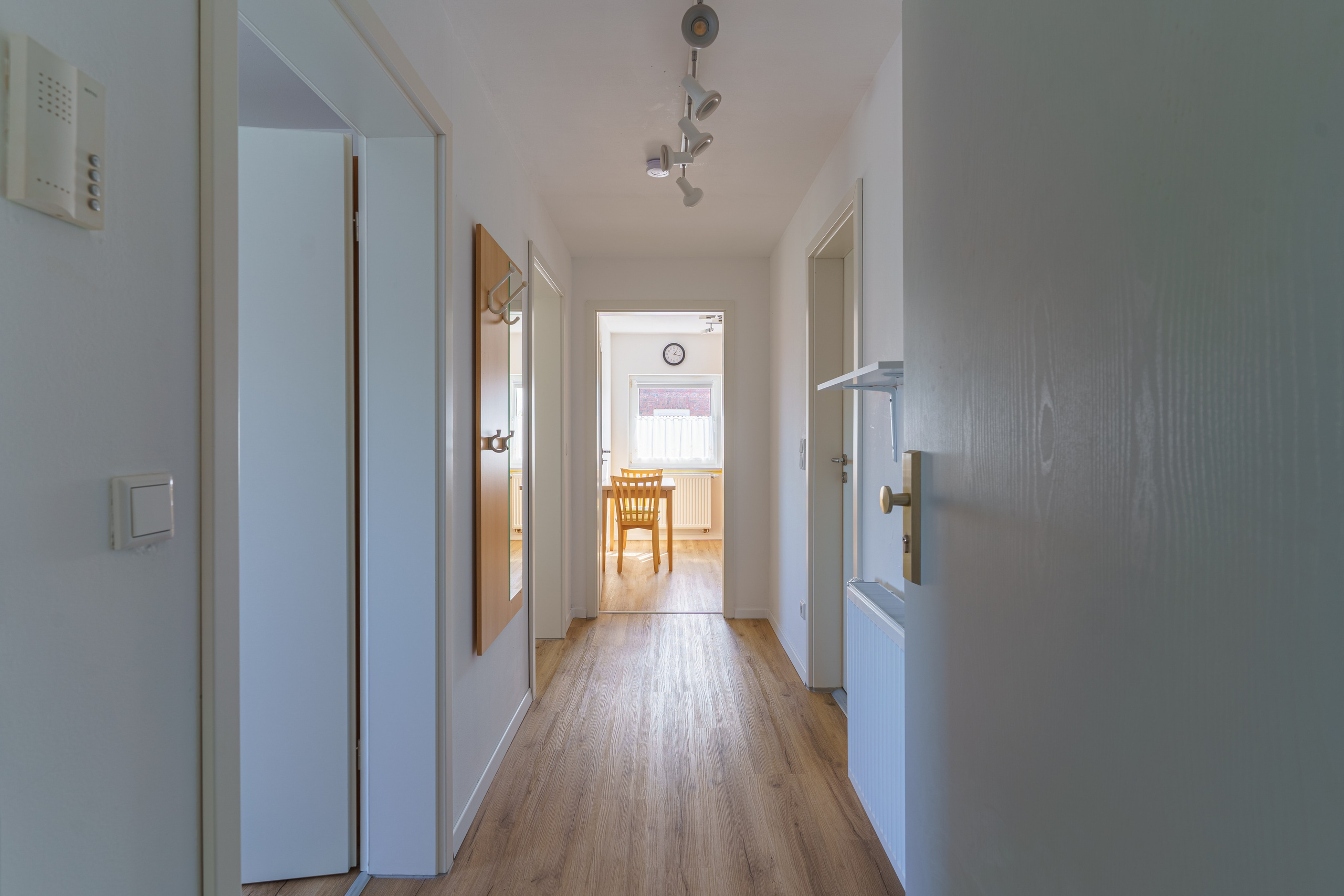 Originale Immobilienfotografie: Heller Flur einer Dachgeschosswohnung mit Holzoptik-Boden und Durchblick in die Räume. Fotografie von jade-visual.