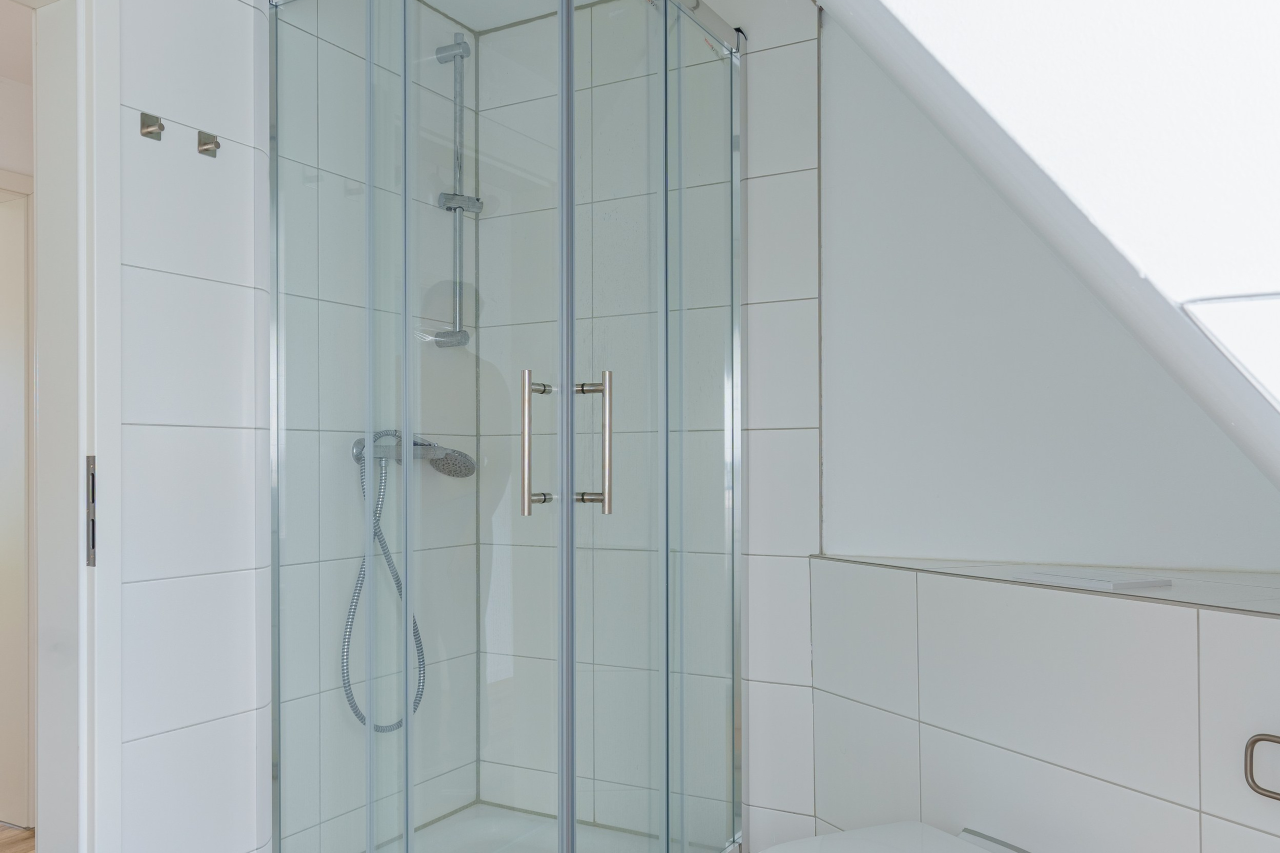 Originale Immobilienfotografie: Modernes Badezimmer im Dachgeschoss mit Eckdusche aus Glas, WC und Fliesen in Holzoptik. Fotografie von jade-visual.