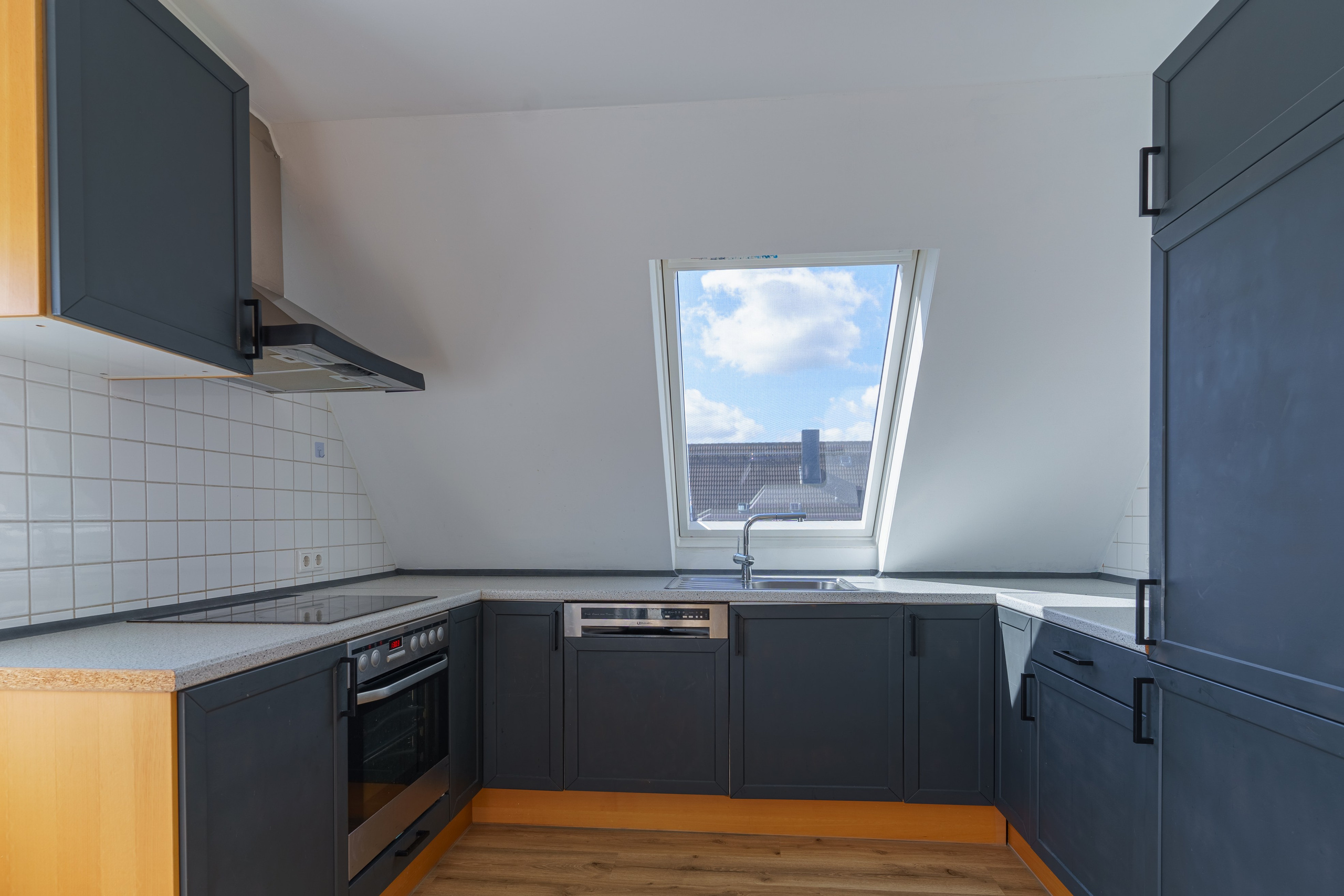 Originale Immobilienfotografie: Dachgeschossküche in U-Form mit dunklen Fronten, Dachfenster und Einbaugeräten. Fotografie von jade-visual.