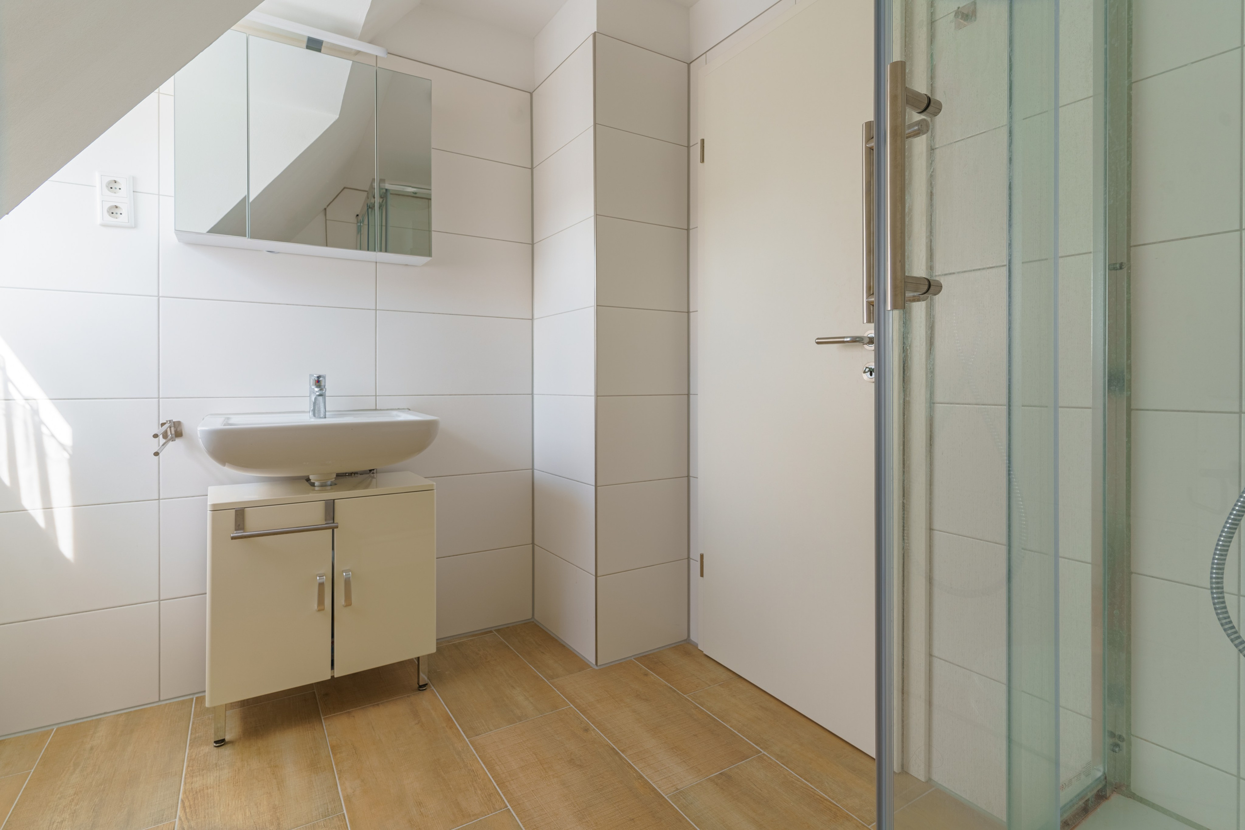 Originale Immobilienfotografie: Badezimmer im Dachgeschoss mit Waschbecken, Unterschrank und Spiegelschrank. Fotografie von jade-visual.