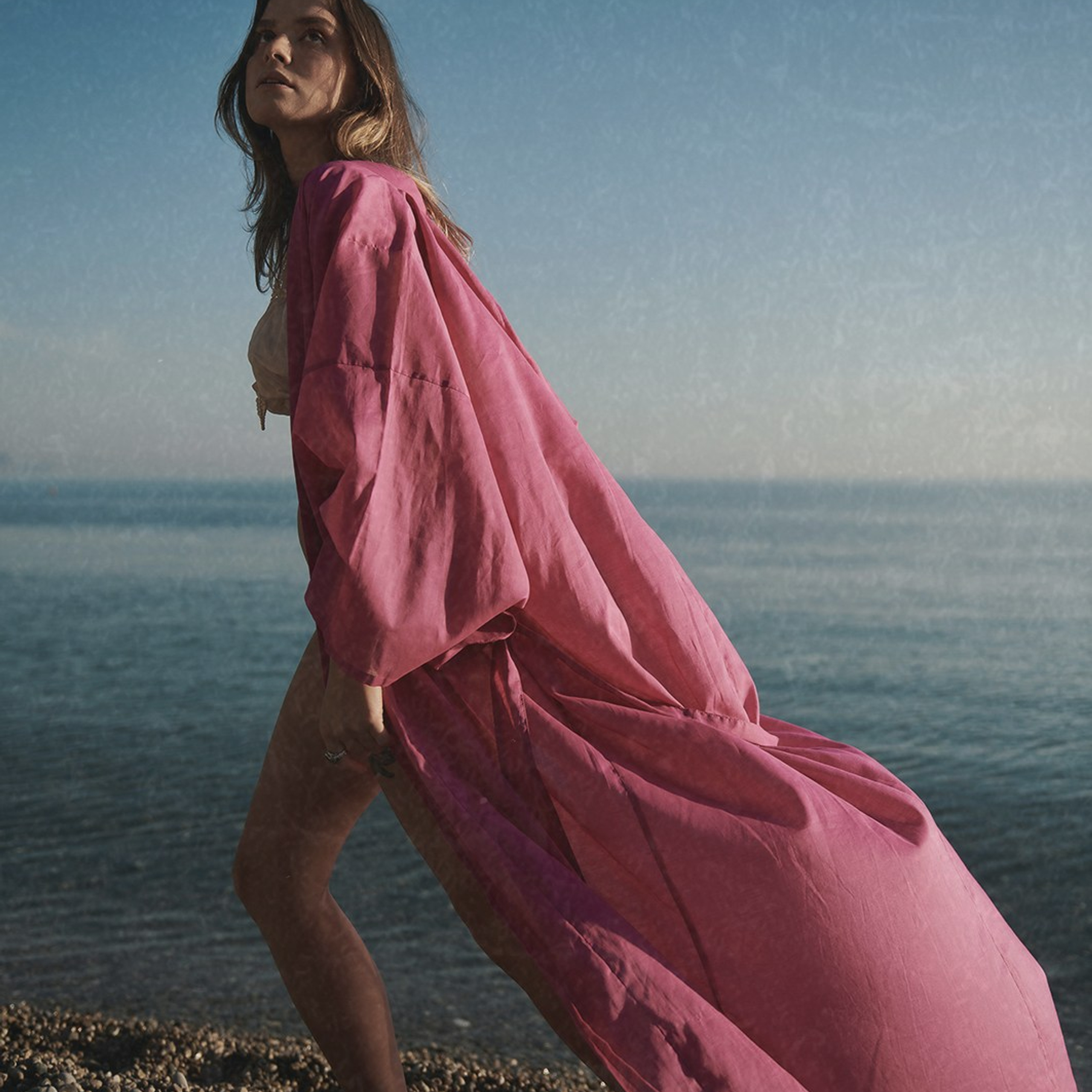 Fashion portrait of a woman in red kimono, photographed on a seashore 