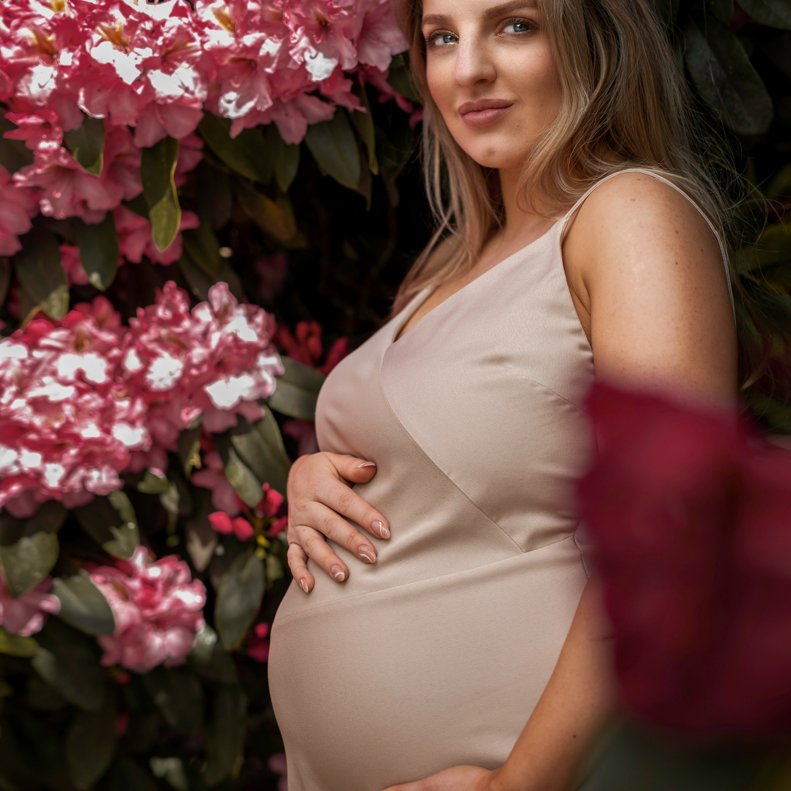 An ethereal portrait of a bride holding her bouquet, surrounded by delicate pink rhododendron blooms in the tranquil gardens of Yorkshire's Harewood House.