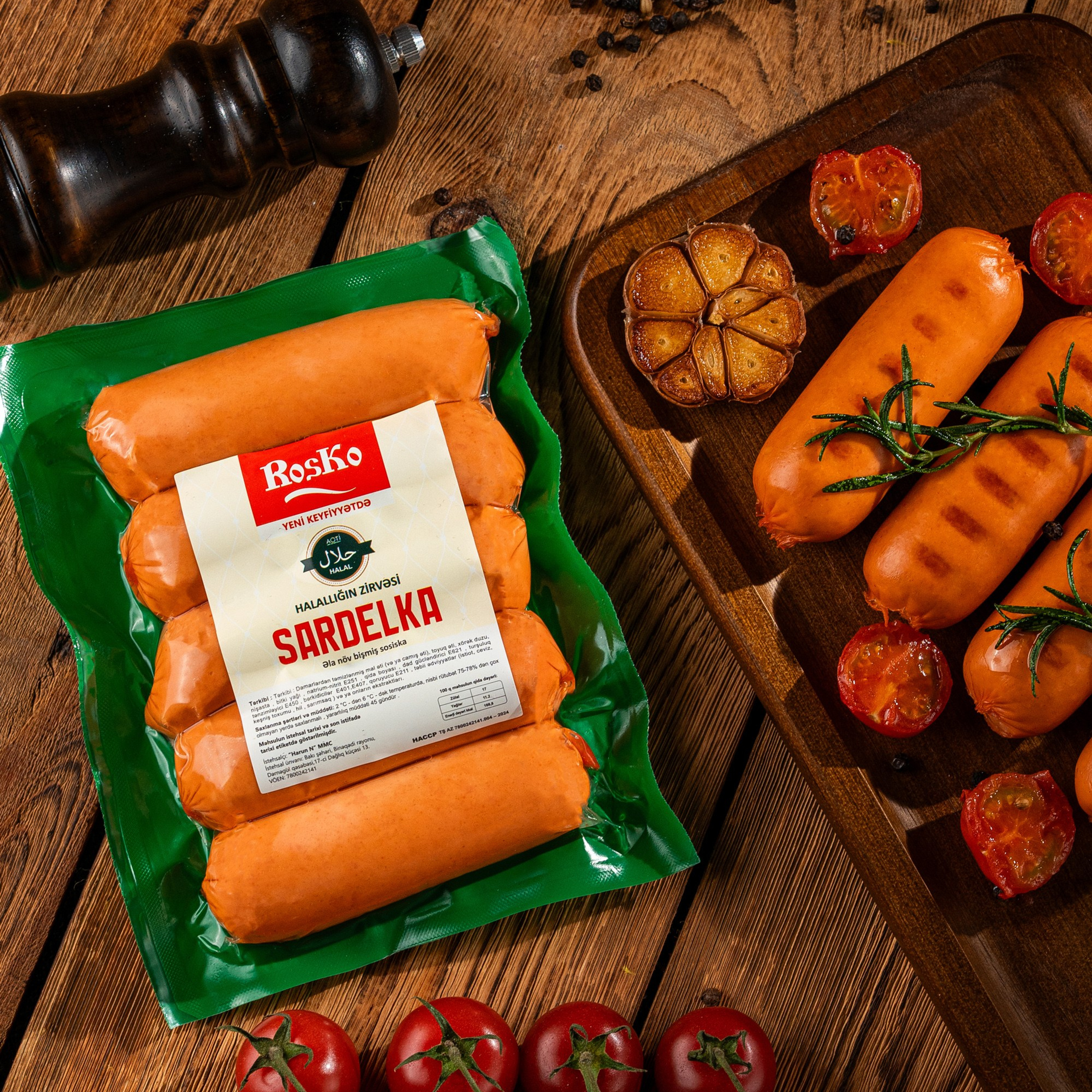 Roska “Sardelka” sosiskaları: paketli və qızardılmış formada, qovrulmuş sarımsaq və pomidorla taxta fonda təqdimat.