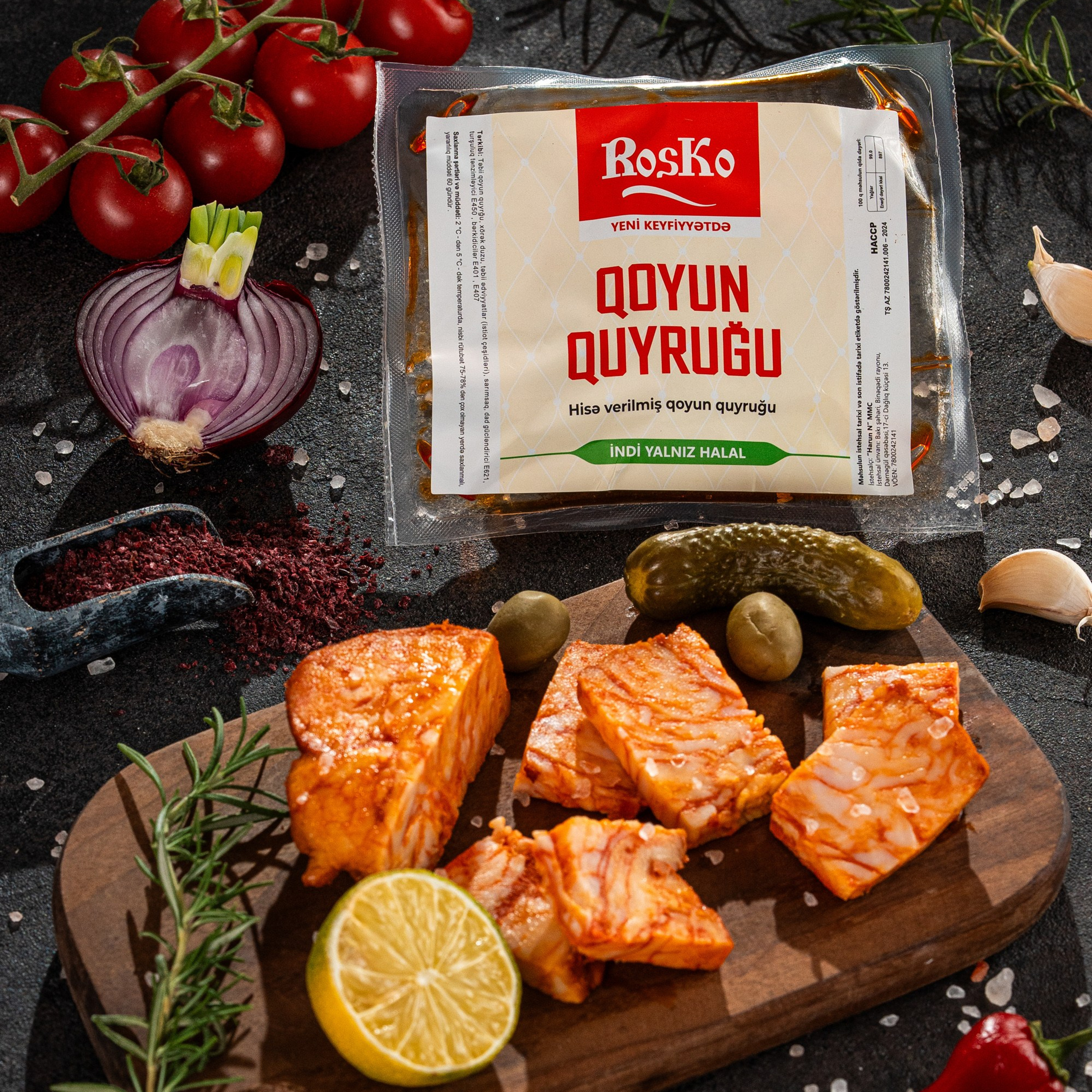 Roska qoyun quyruğu məhsulu, paketli və doğranmış formada limon, turşu və qarnir elementləri ilə qara fonda təqdim olunub.