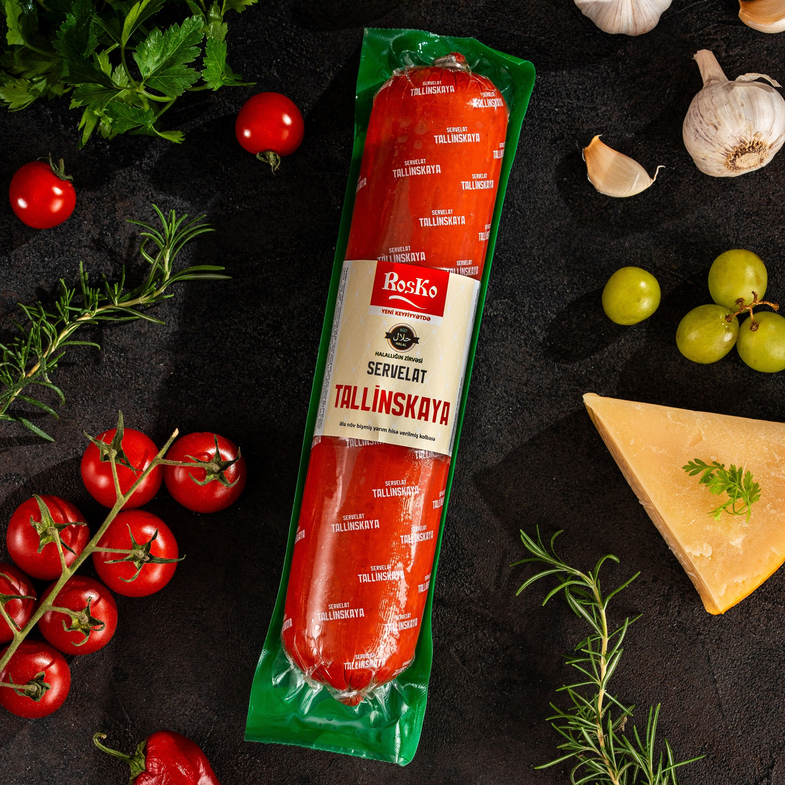 Roska “Tallinskaya” servelat kolbasası tünd fon üzərində üzüm, pomidor, pendir və otlarla zəngin stilizasiya olunmuş qida vizualı.