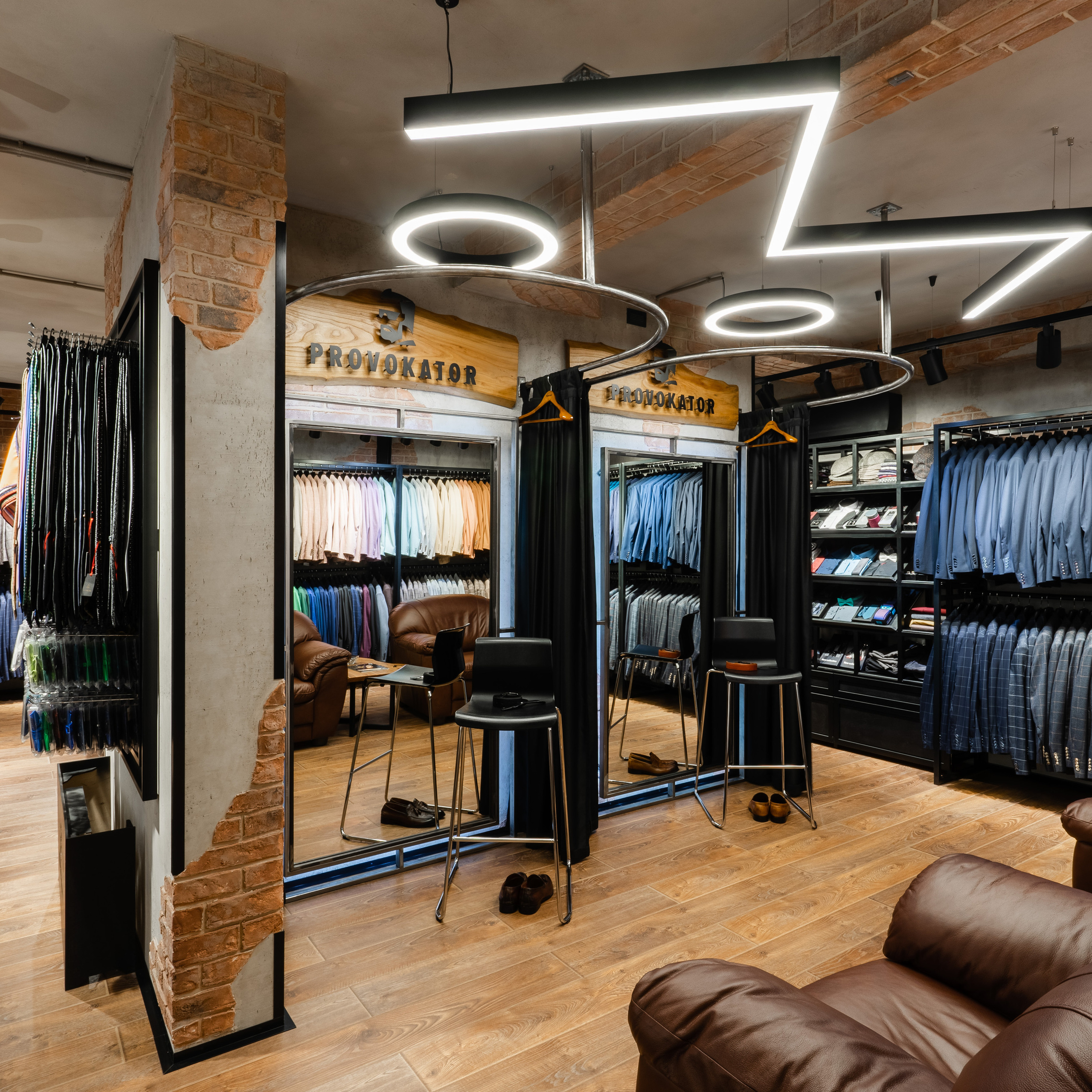Fashionable menswear store with a rustic chic vibe, illuminated by creative overhead lighting that casts geometric shadows, shot with a wide-angle lens to capture the full context of the retail environment